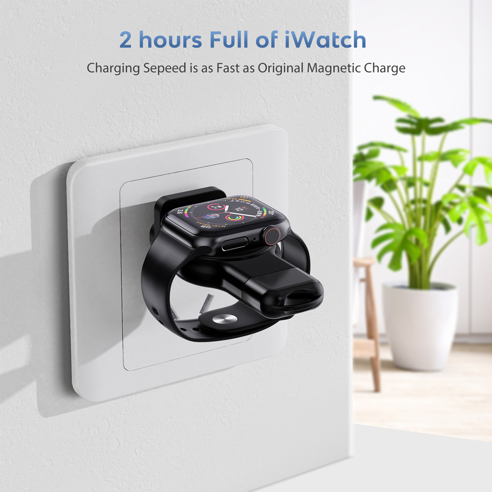 Eine schwarze Smartwatch wird an einem Wandladegerät mit einer grünen Pflanze im Hintergrund aufgeladen.