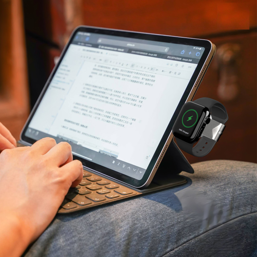 Person, die ein Tablet mit Tastatur verwendet; Uhr wird magnetisch geladen.