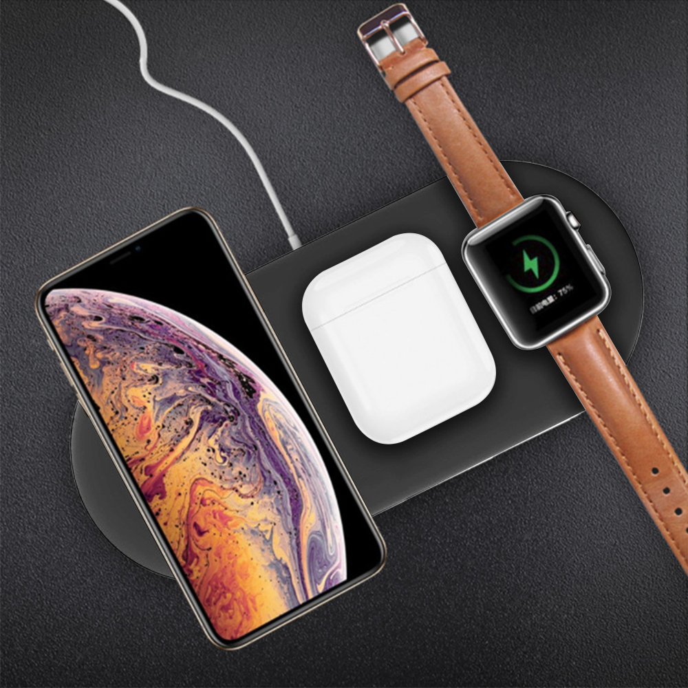 Ein Telefon, Ohrhörer und eine Uhr, die auf einem schwarzen kabellosen Ladepad aufgeladen werden.