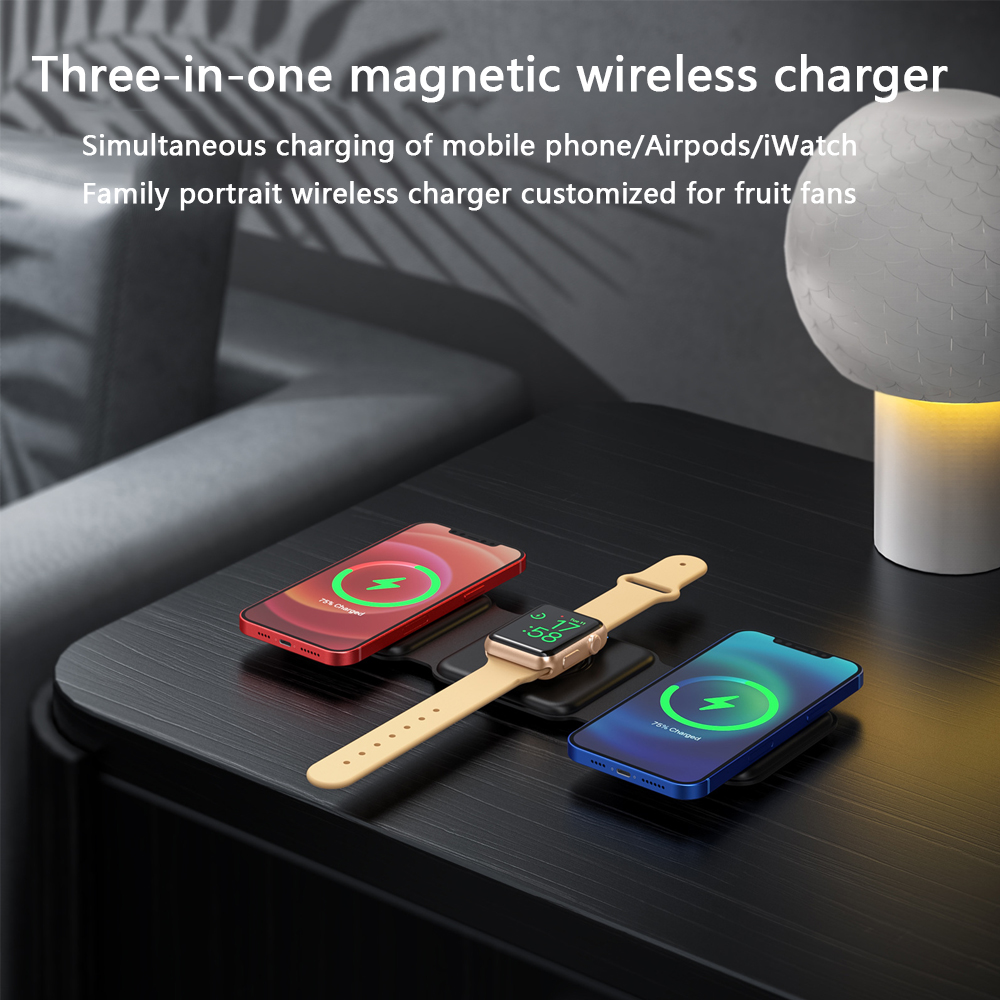 Ein schwarzes, zusammenklappbares Drei-in-Eins-Wireless-Ladegerät, das zwei Telefone und eine Uhr auf einem schwarzen Tisch auflädt.