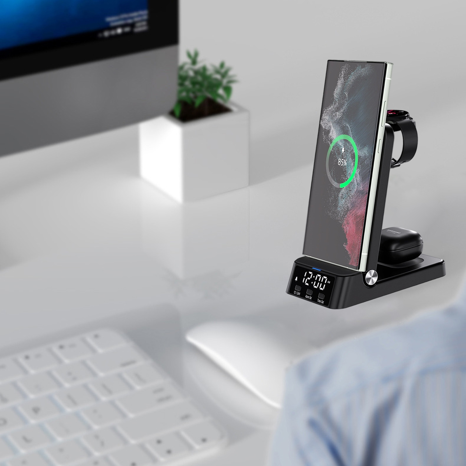 Eine Ladestation mit einem Telefon, einer Uhr und Ohrhörern auf einem Schreibtisch, Telefon bei 85 %.