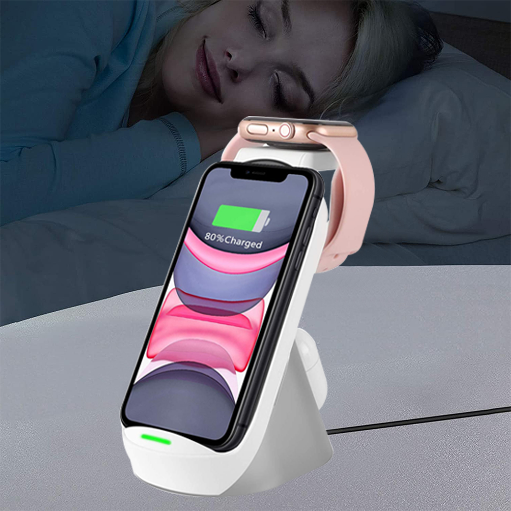 Eine kabellose Ladestation, die ein Telefon und eine Uhr neben einer schlafenden Frau auflädt.