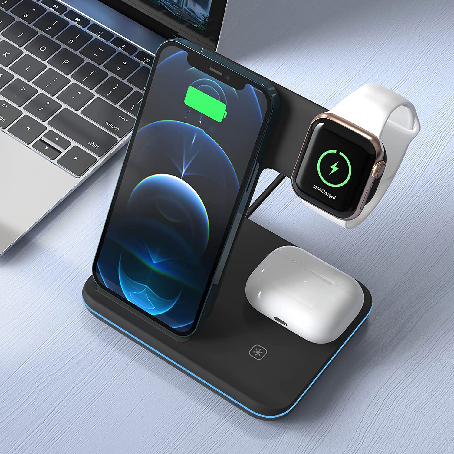 Eine Ladestation hält ein Telefon, eine Uhr und Ohrhörer, die alle anzeigen, dass sie geladen werden, auf einer blauen Oberfläche.