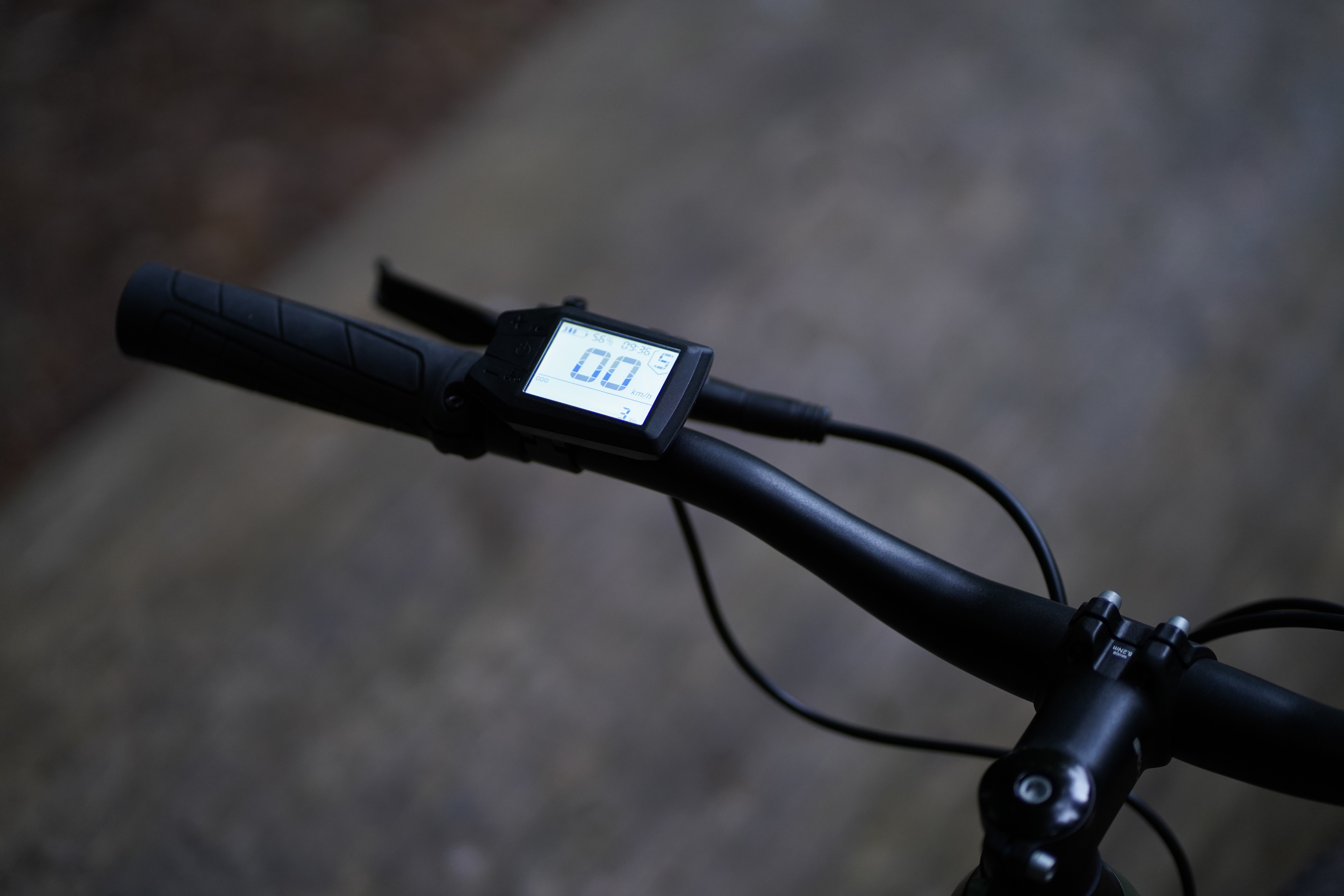 Die Nahaufnahme des Lenkerdisplays eines Fahrrads zeigt „0.0“ auf dem Bildschirm vor einem verschwommenen Outdoor-Hintergrund.