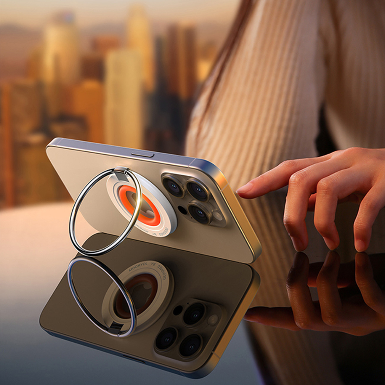 Telefon z podstawką na pierścień na odblaskowej powierzchni. Tło jest rozmyte ze światłami miasta.