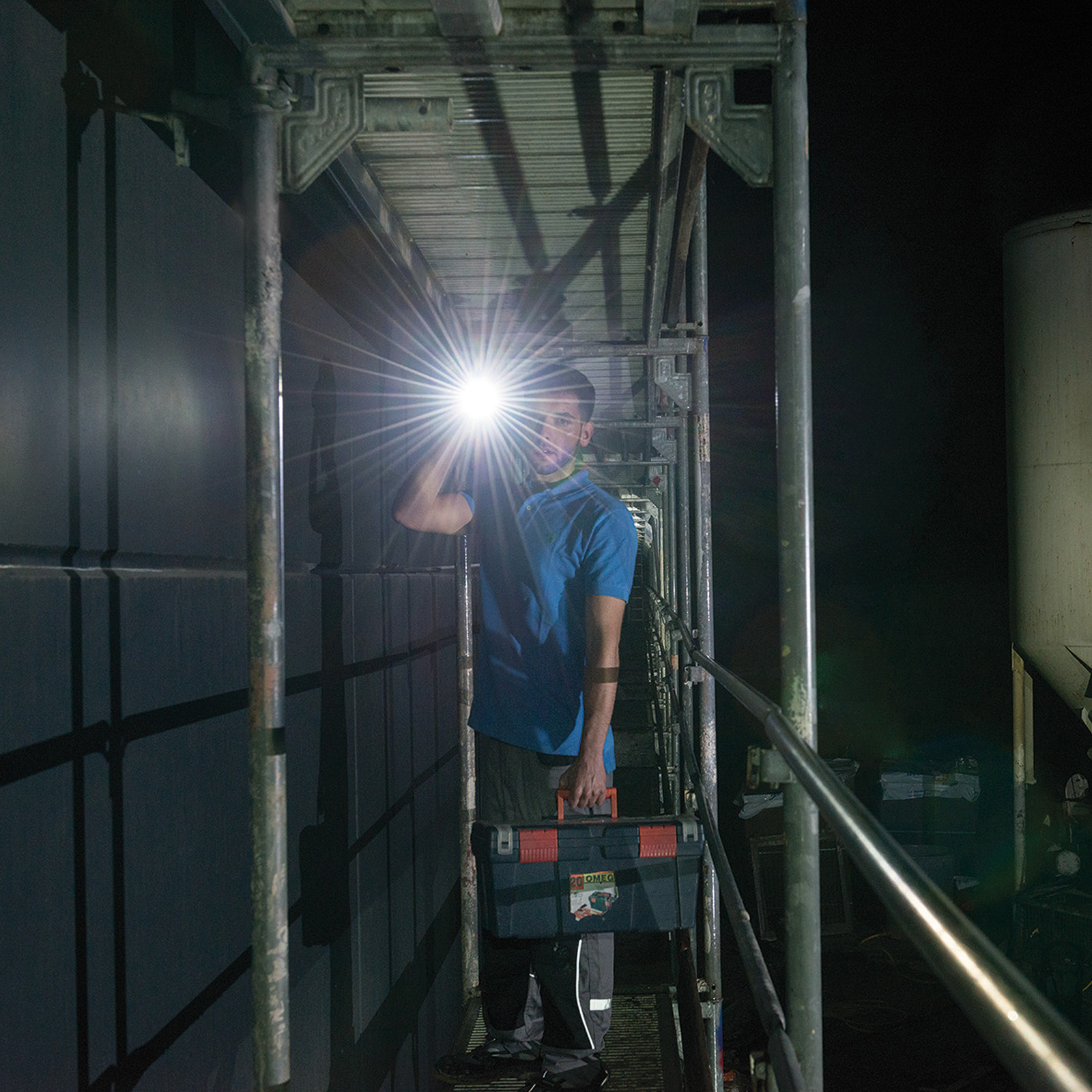 Osoba świeci latarką na metalowe rusztowanie. Światło świeci jasno.