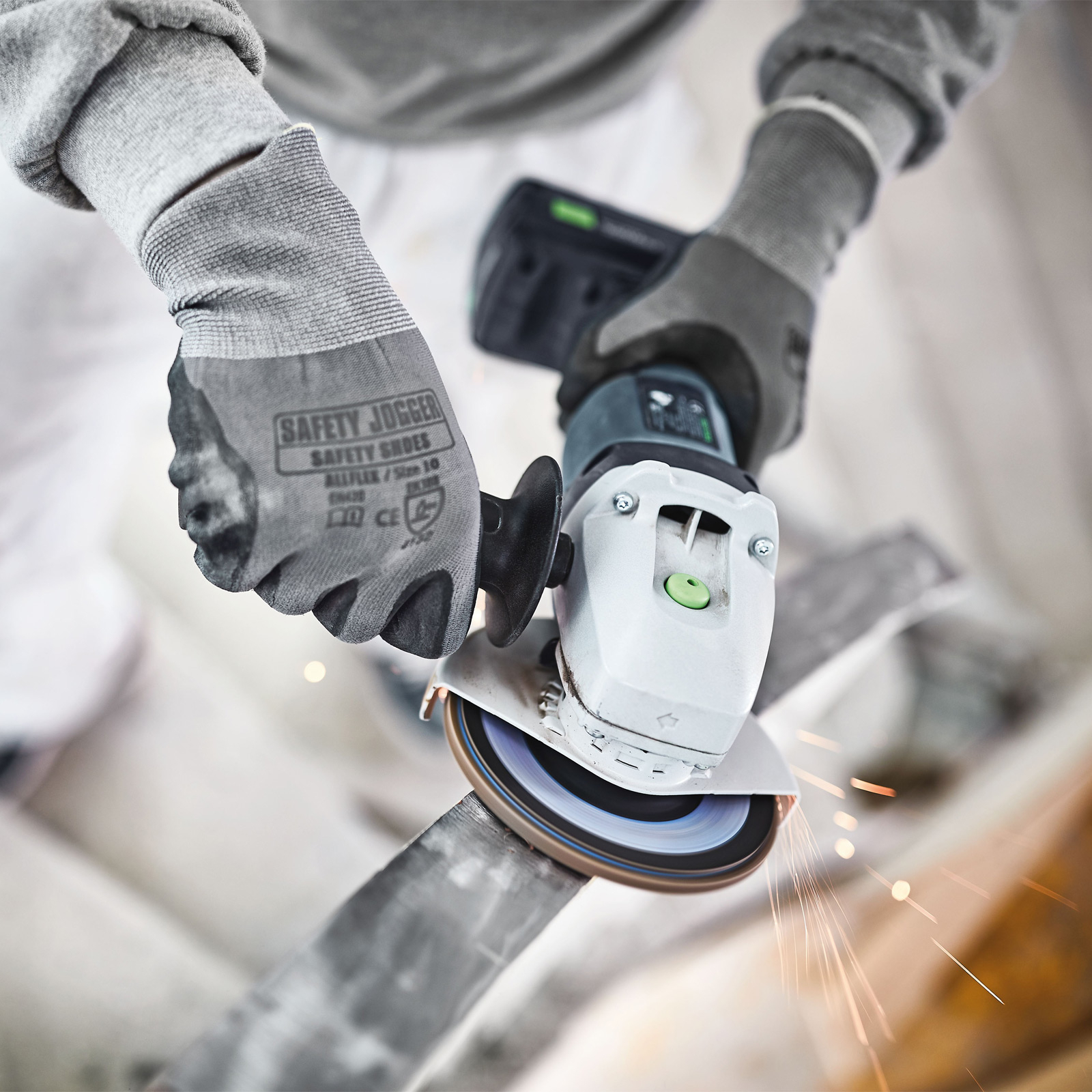 Una persona con guantes está esmerilando metal, creando chispas con una amoladora angular Festool.