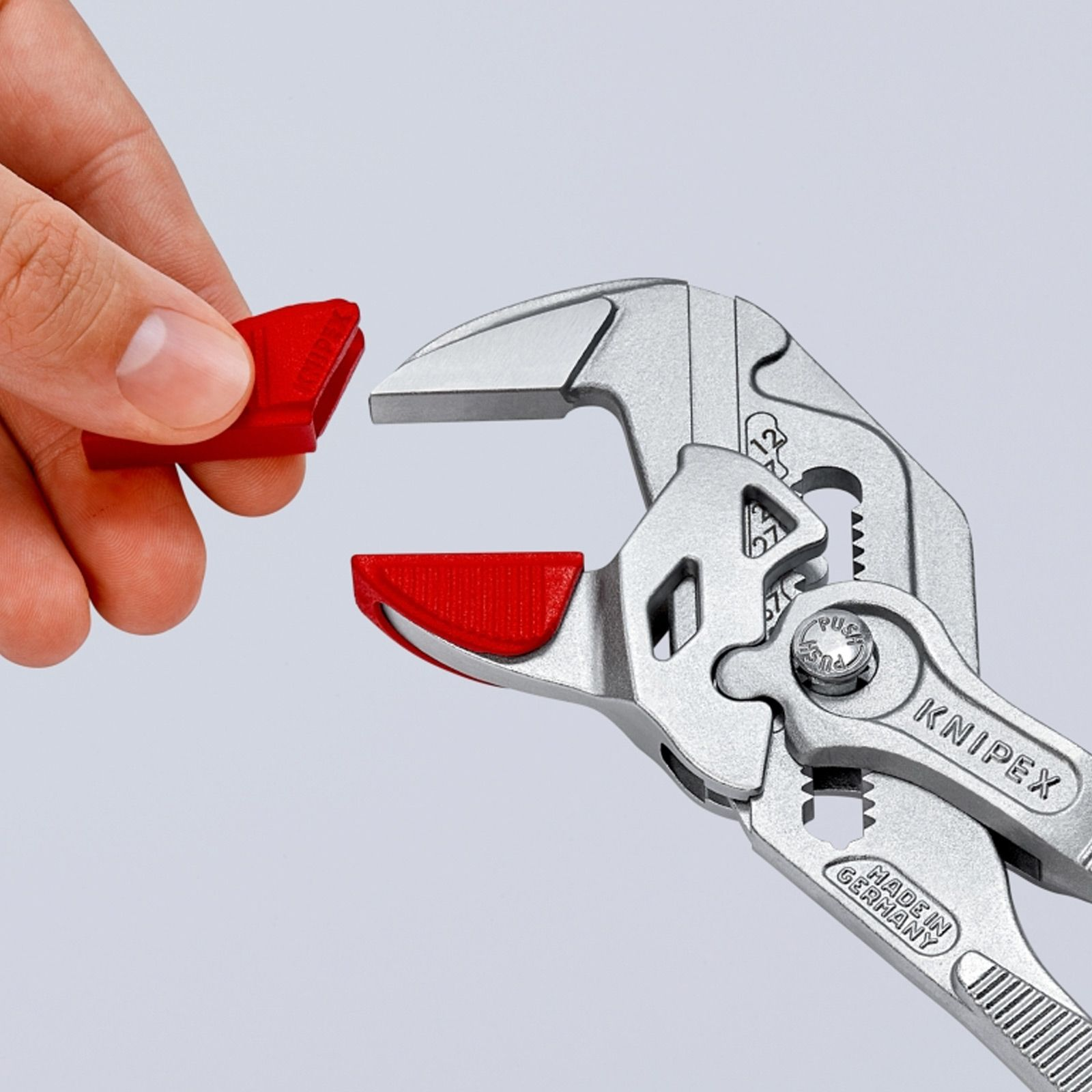 Silver pliers with red rubber tips being added by a hand, showcasing the tool's versatility.