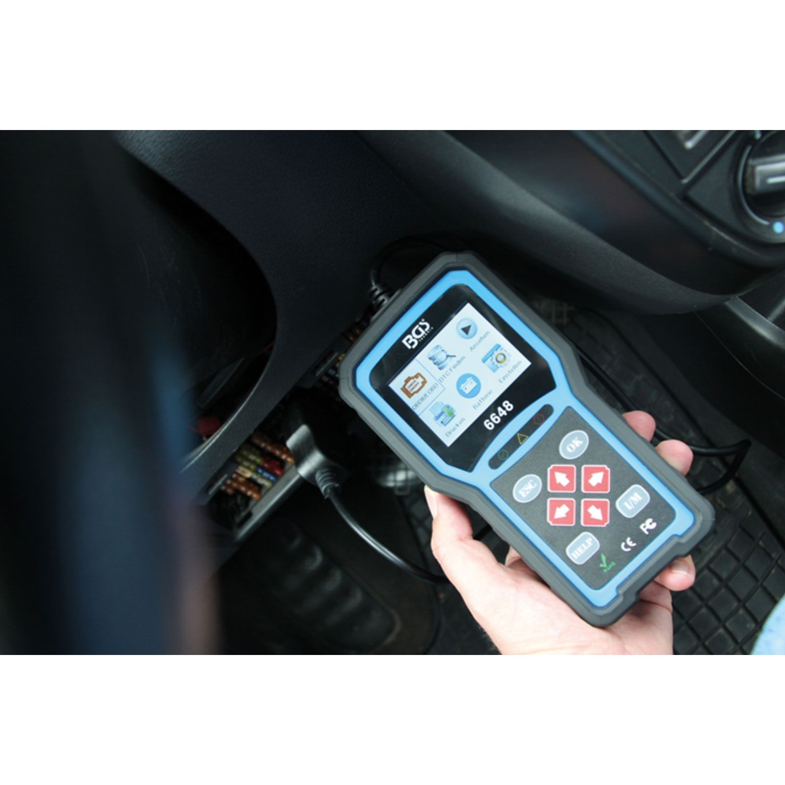 Ein Diagnose-Scanner in der Hand. Es hat einen Bildschirm mit mehreren Symbolen und einen blau-schwarzen Rahmen.