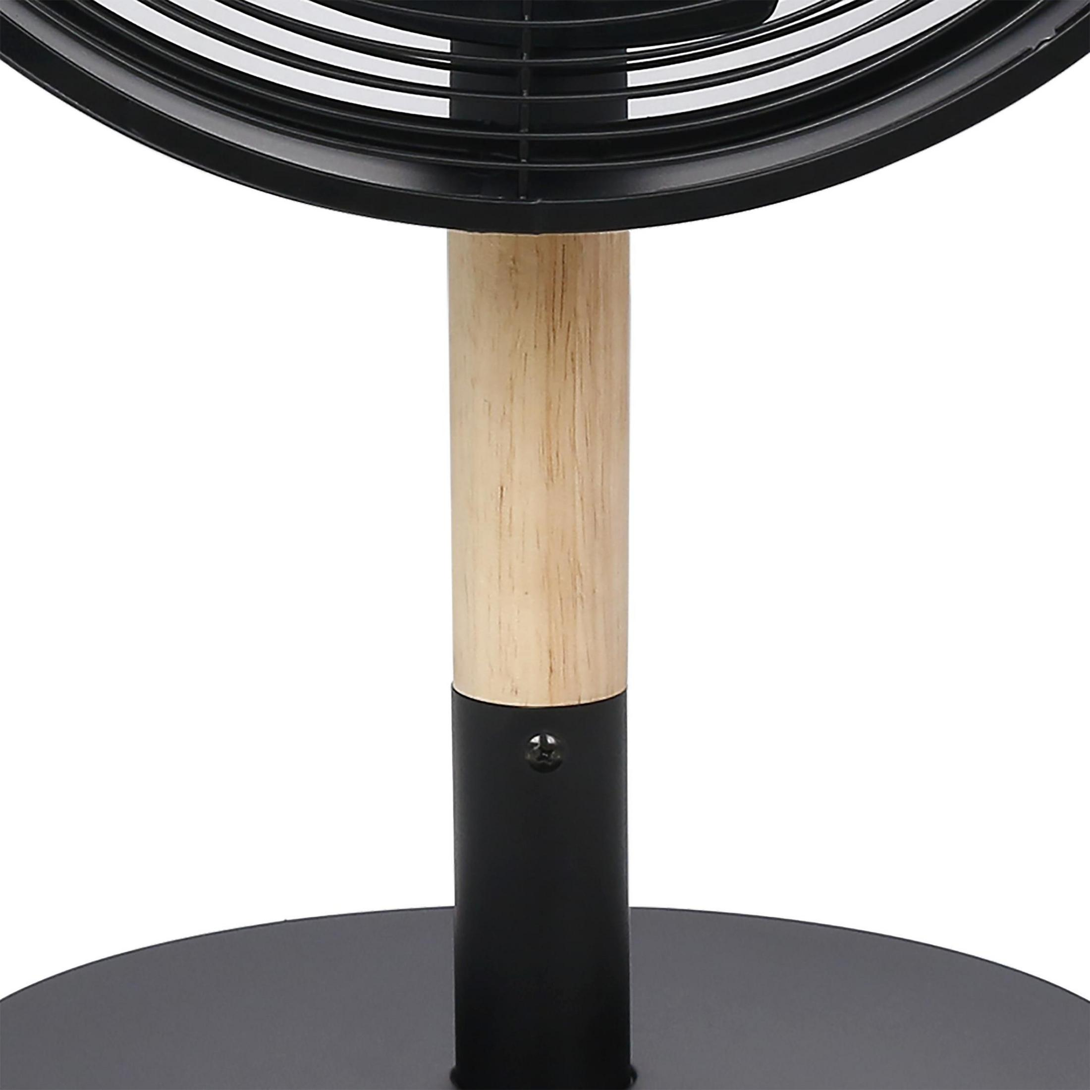 Se muestra un ventilador negro con un soporte de madera y metal contra un fondo blanco.