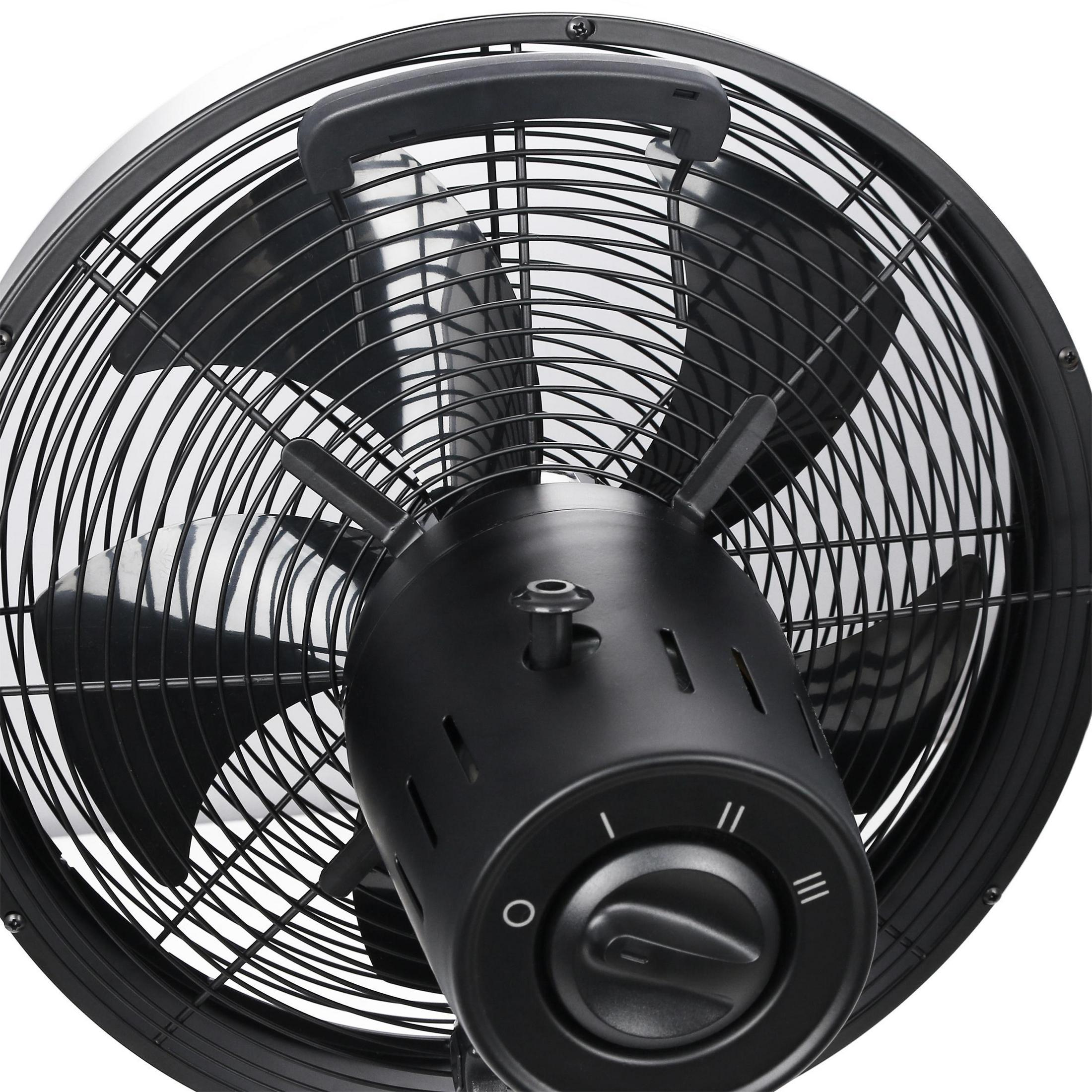 Un primer plano de un ventilador industrial negro, que muestra sus aspas, jaula y dial de control de velocidad.