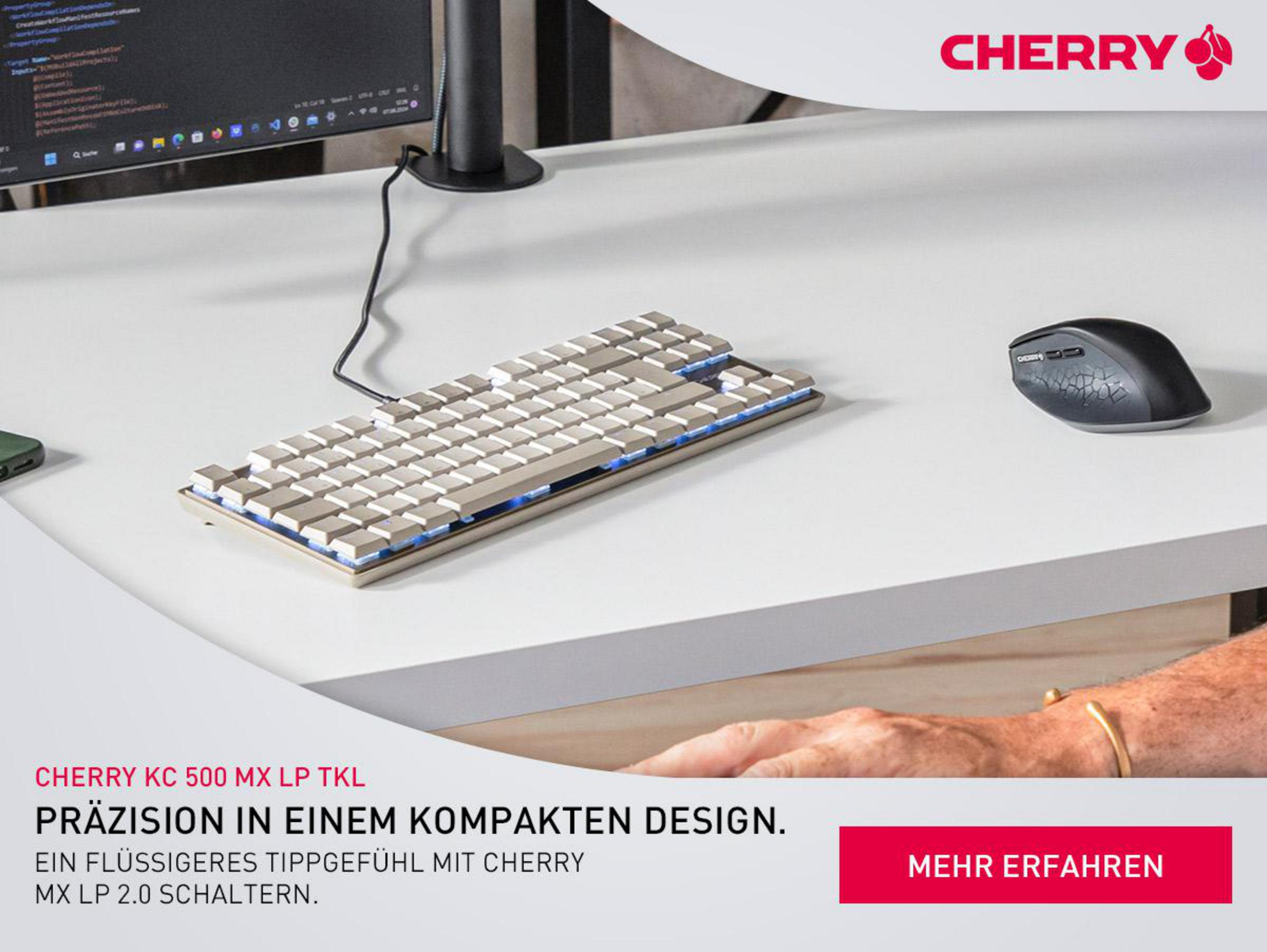 Eine Cherry-Tastatur und -Maus auf einem weißen Schreibtisch mit einem Monitor im Hintergrund, Produktwerbung.