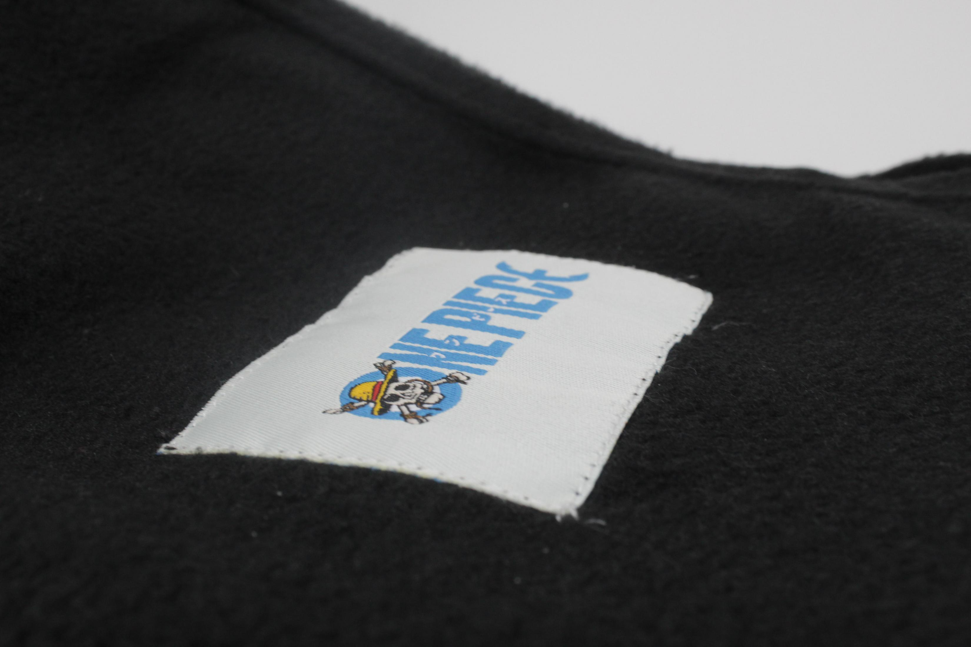 Nahaufnahme eines Etiketts auf einer schwarzen One Piece Decke mit dem Logo des Animes.