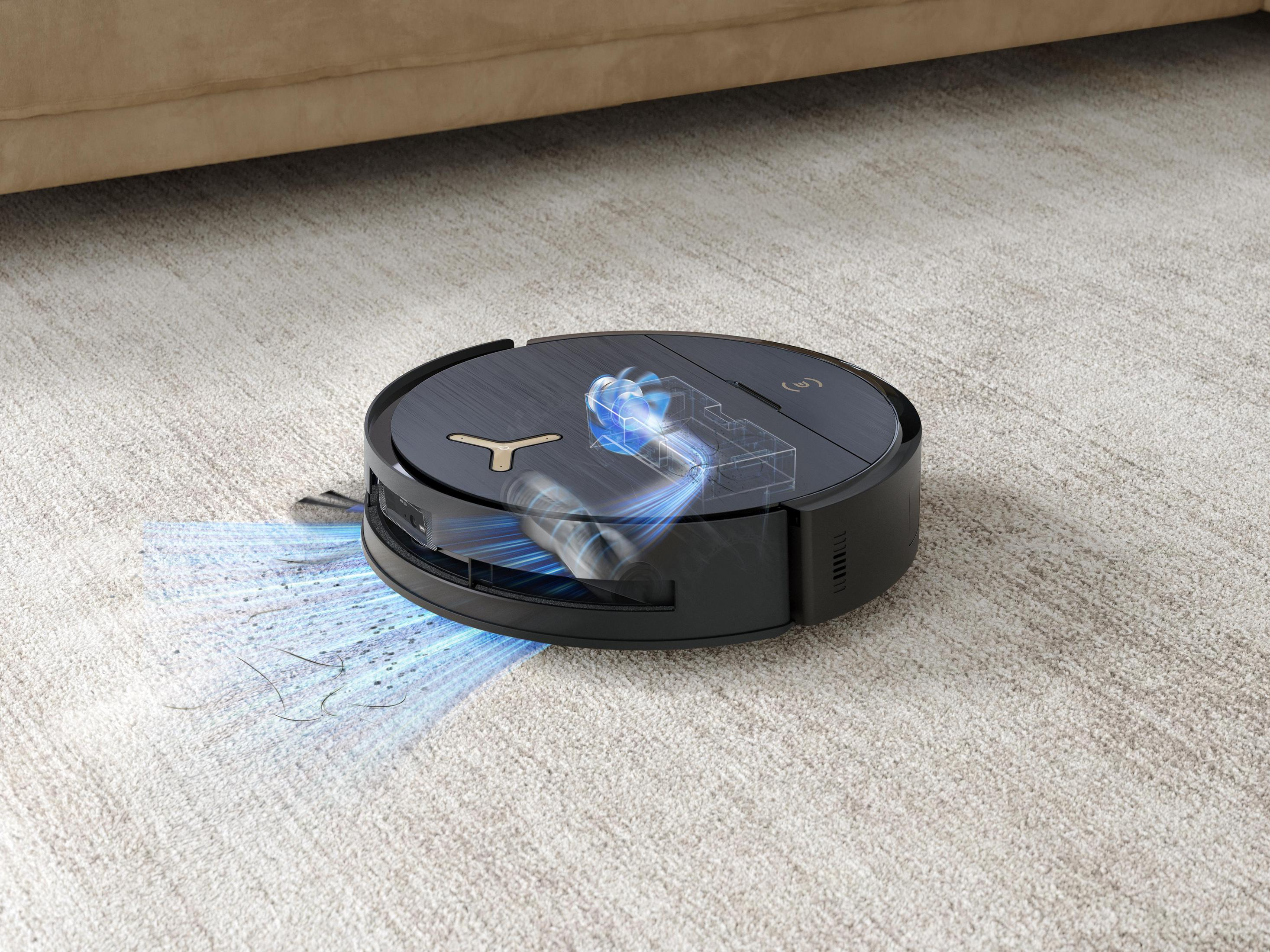 Ein schwarzer Roboterstaubsauger auf einem Teppich, mit blauem Licht, der Haare und Schmutz aufsaugt.