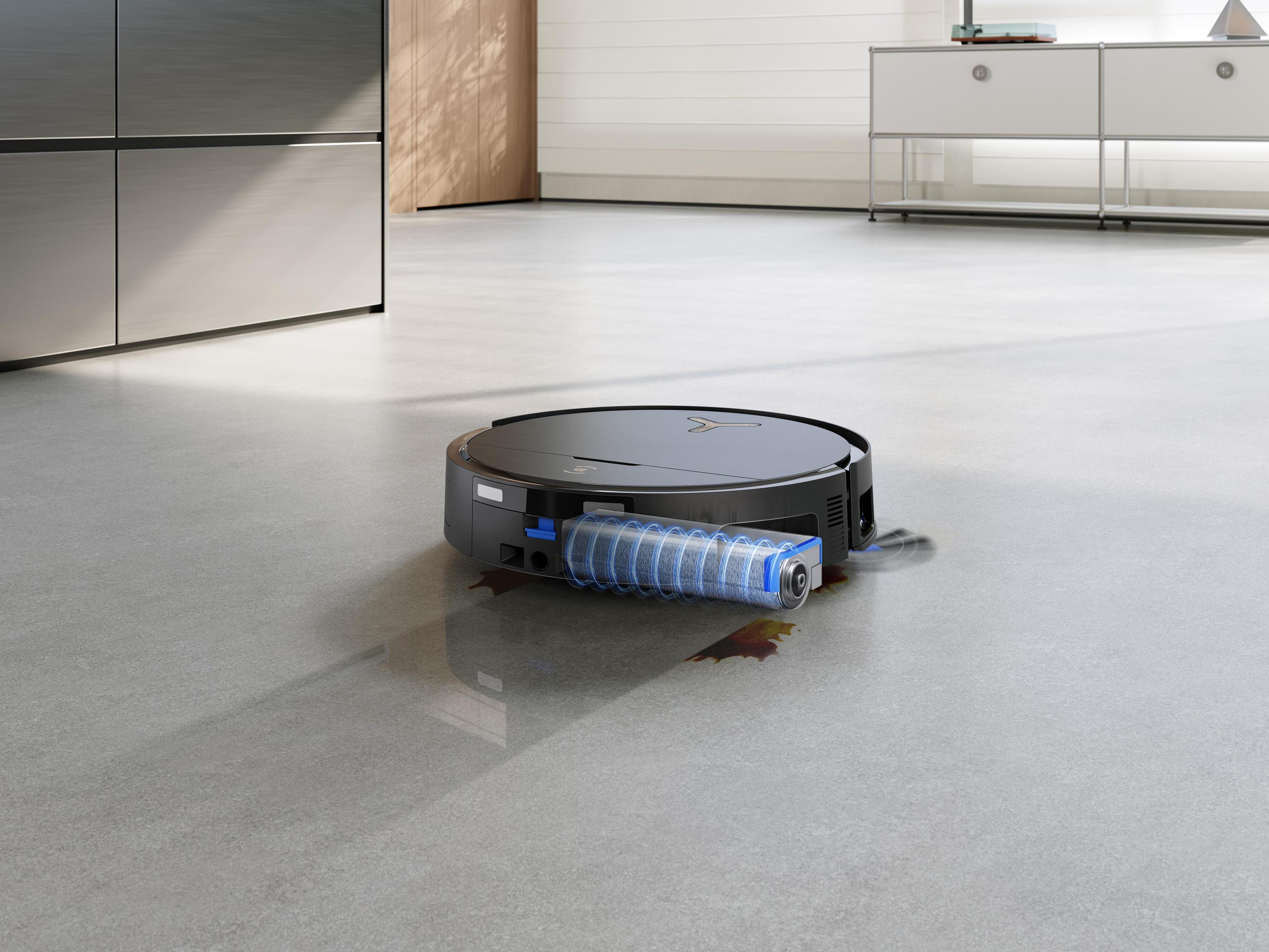 Ein schwarzer Roboterstaubsauger auf einem grauen Boden, mit blauem Licht, der einen Fleck reinigt.