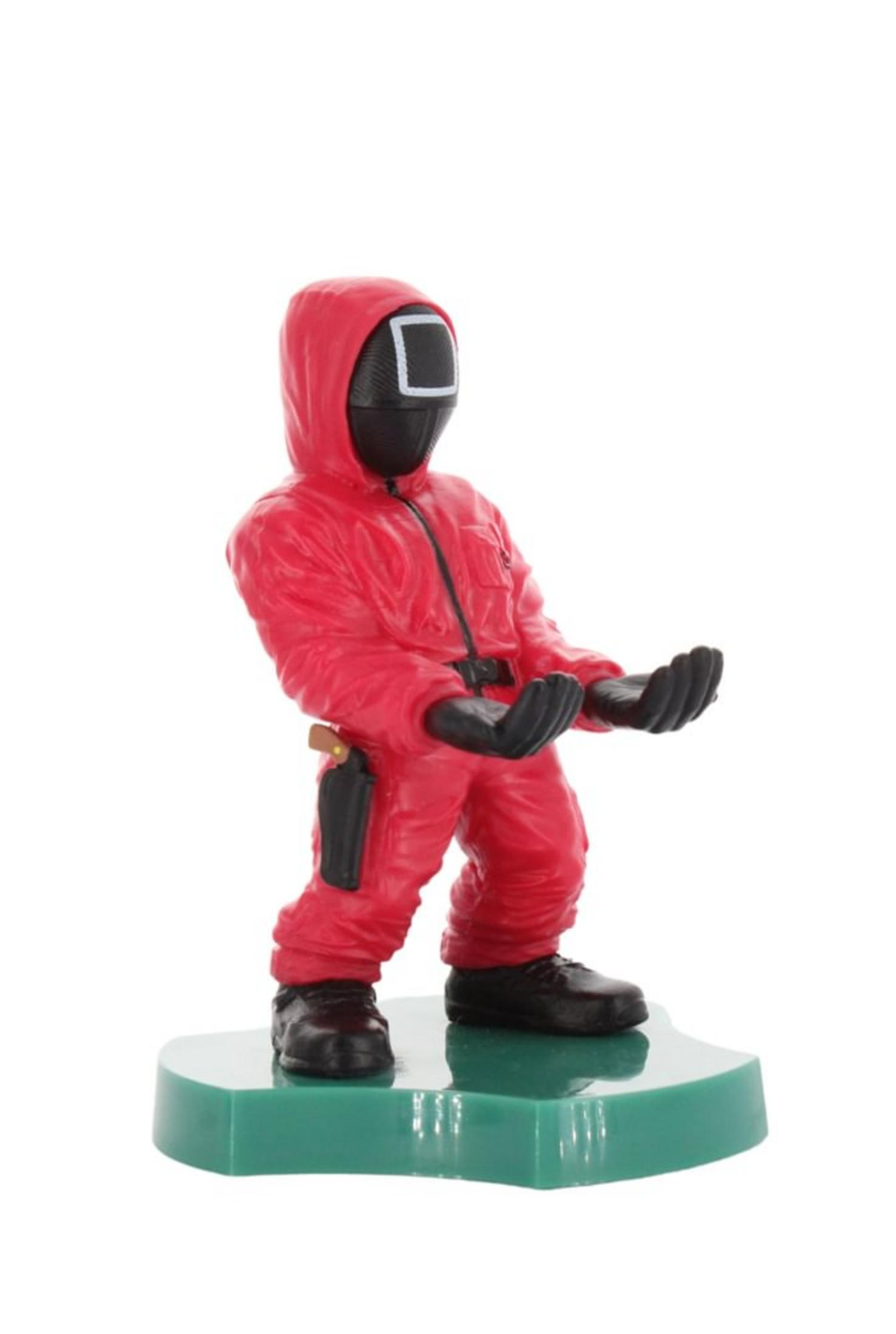 Eine Squid Game Masked Manager-Figur in einem roten Anzug hält die Hände aus. Sie steht auf einem grünen Sockel.