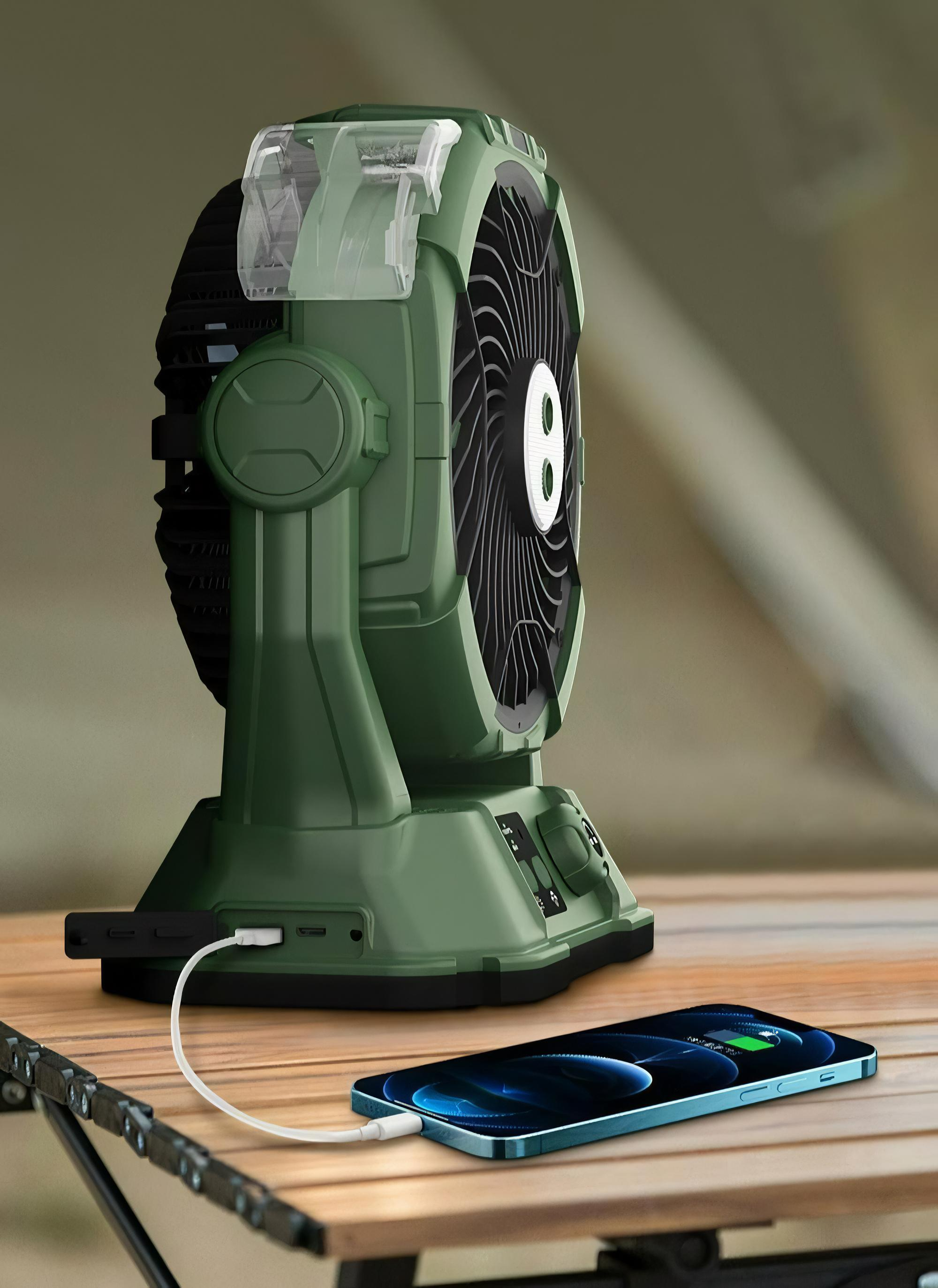 Grüner Campingventilator mit Lichtern lädt ein Telefon auf einem Holztisch auf. Die Lüfterflügel sind sichtbar.