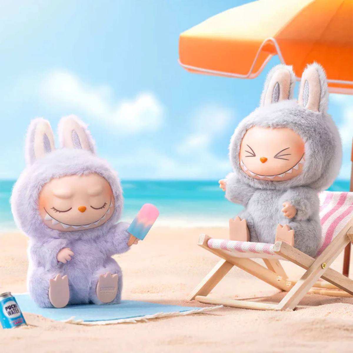 Zwei Plüschhasen sitzen an einem Strand unter einem orangefarbenen Sonnenschirm; einer hält ein Eis am Stiel und eine Dose Limo steht in der Nähe.