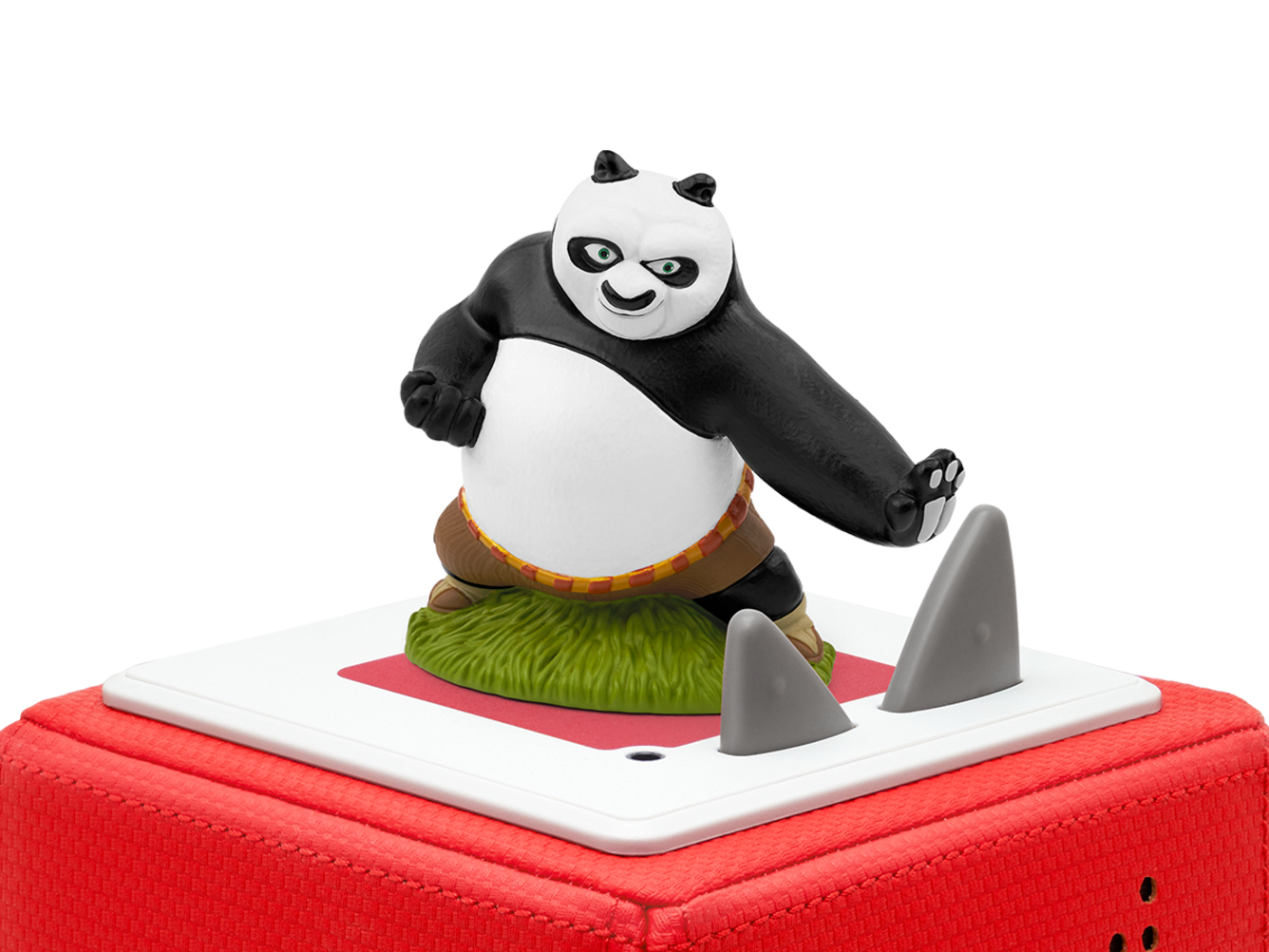 Eine Kung Fu Panda-Figur auf einer roten Kiste mit grauen Haifischflossen, vor einem weißen Hintergrund.
