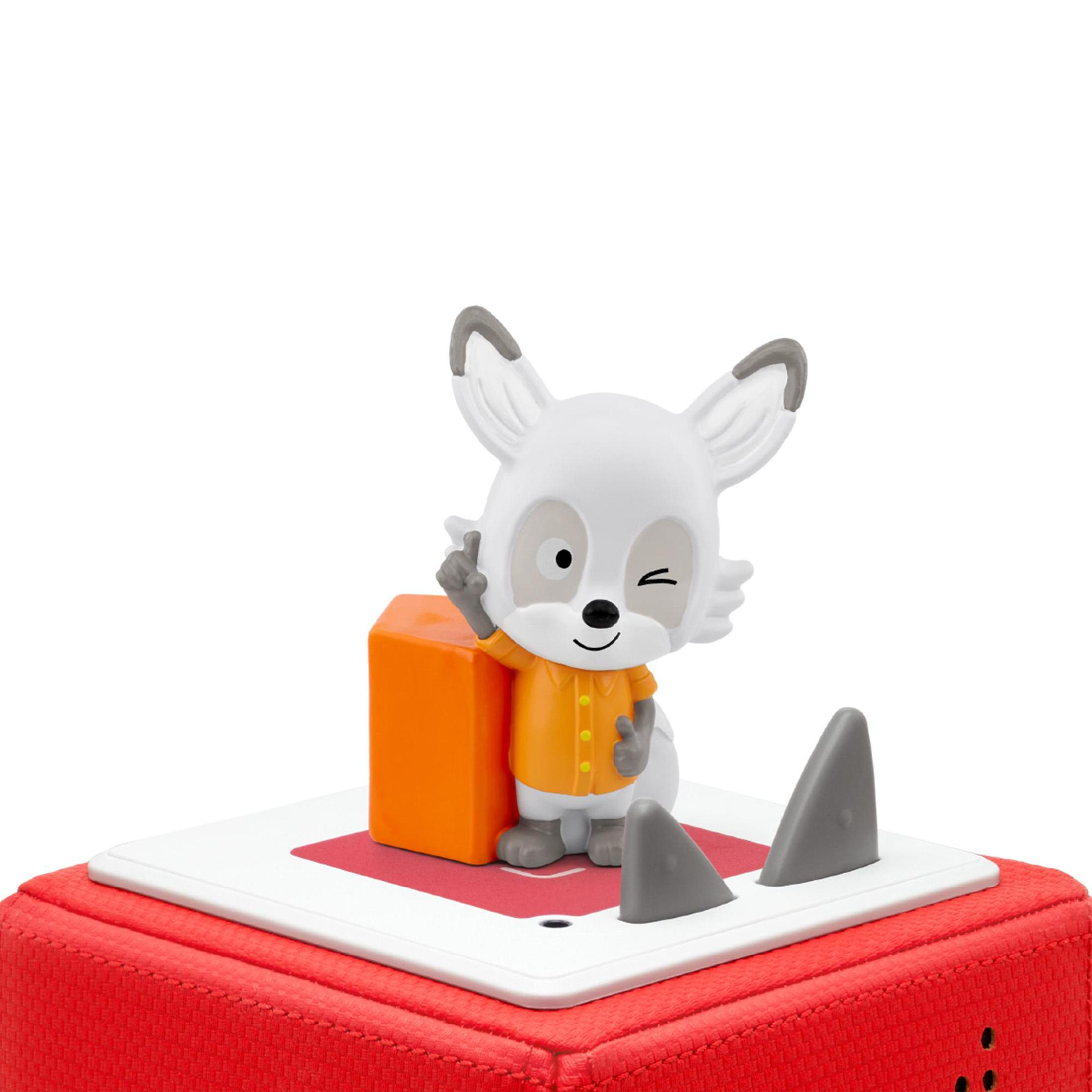 Un personnage jouet Lalalinos avec une chemise orange, des accents gris et un œil qui cligne se tient sur une boîte rouge et blanche.