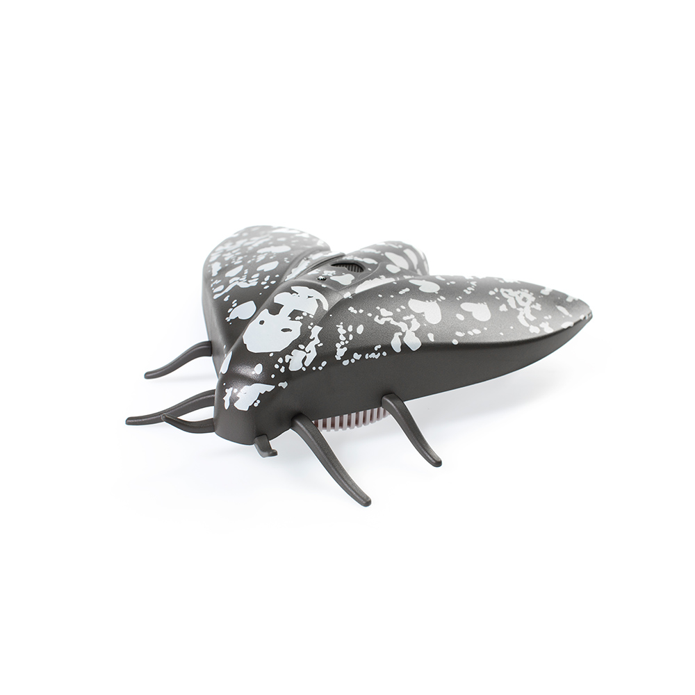 A black, fly-shaped object with white spots on a white background, side view.