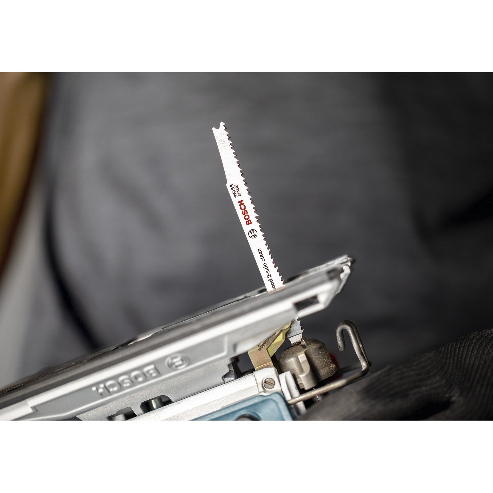 Zbliżenie brzeszczotu wyrzynarki tnącego drewno. Ostrze jest oznaczone jako Bosch.