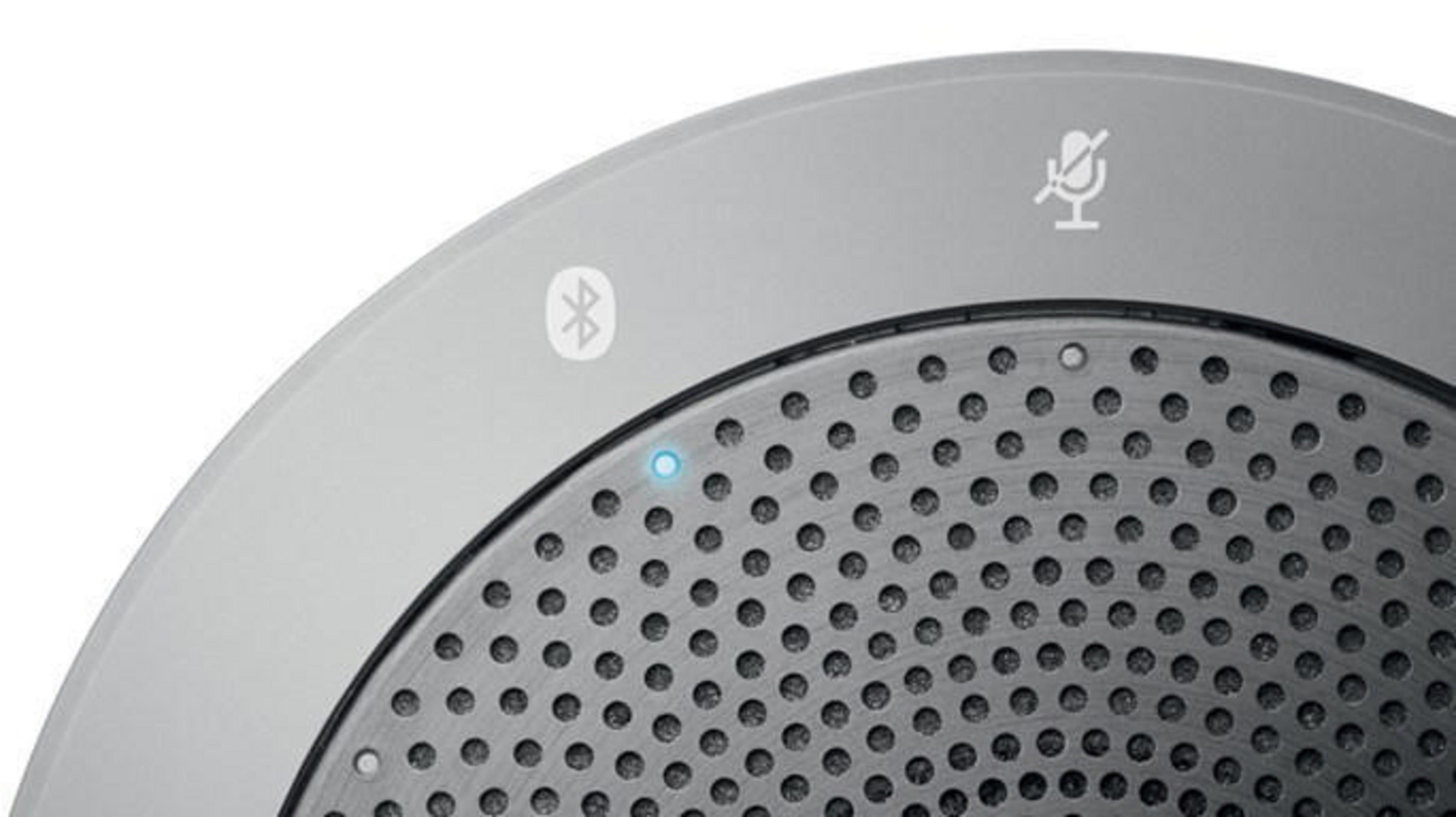 Nahaufnahme eines grauen Lautsprechers mit Bluetooth- und Stummschaltsymbolen, der sein Design und seine Funktionen zeigt.