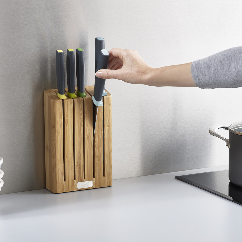 Una mano introduce un cuchillo en un bloque. Cuchillos en encimera de cocina.