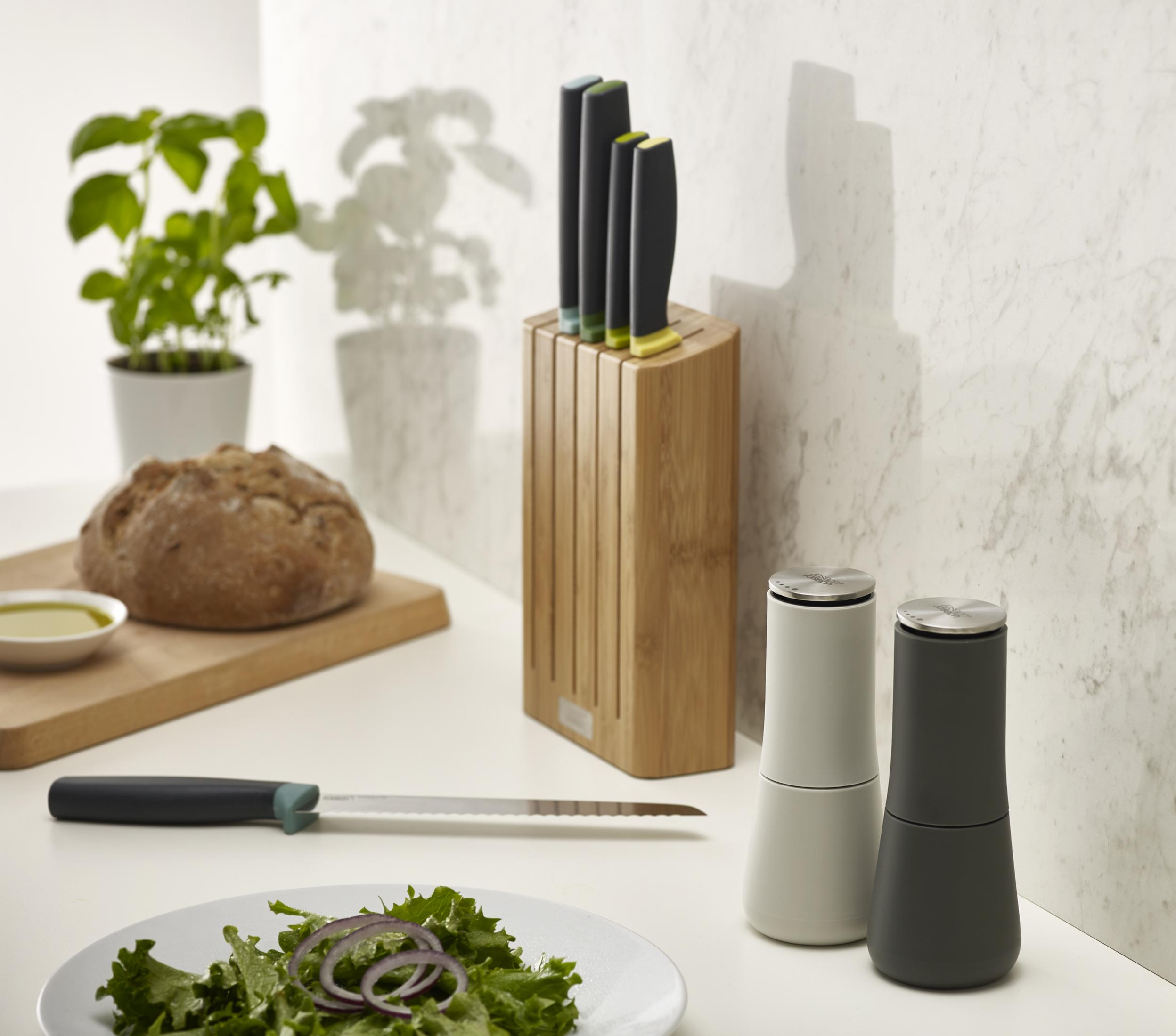 Escena de cocina con un bloque de cuchillos, cuchillos y otros utensilios. Encimera blanca.