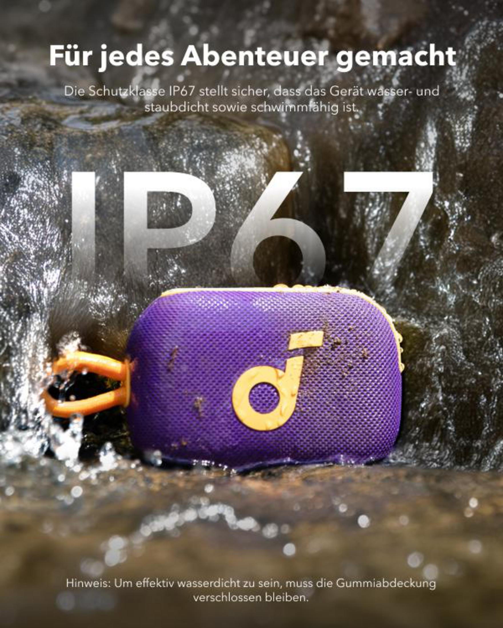 Un altoparlante portatile viola e giallo è posizionato su rocce vicino all'acqua, etichettato IP67.