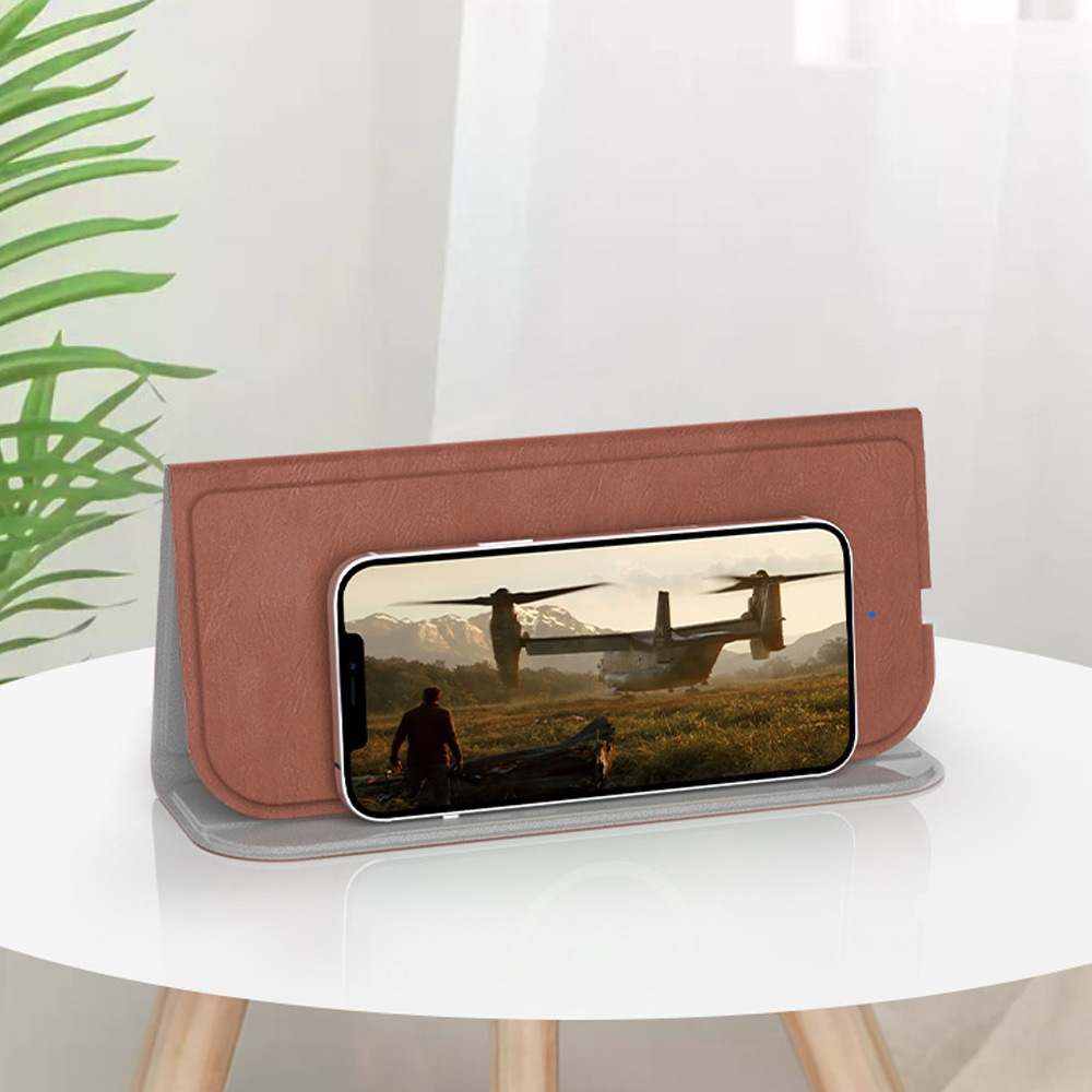 Braunes Telefon auf Ständer zeigt Flugzeug, Mann geht auf Feld, Tisch, Pflanze im Hintergrund.