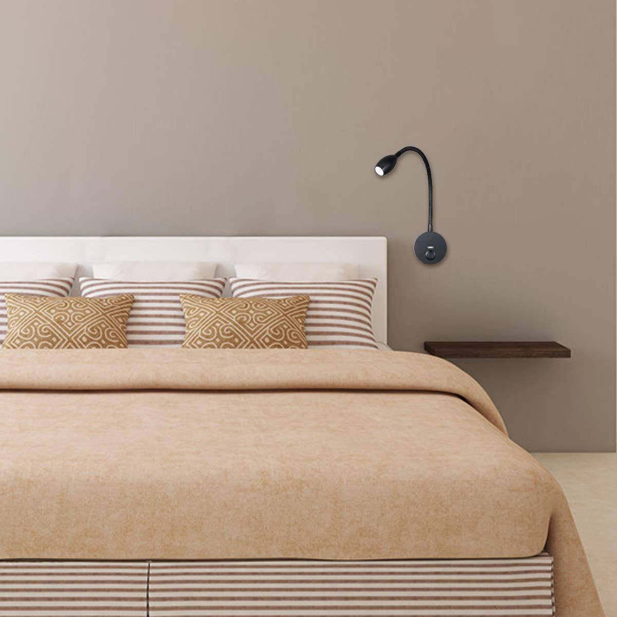 Eine schwarze Wandlampe über einem Bett mit Kissen und Decke.