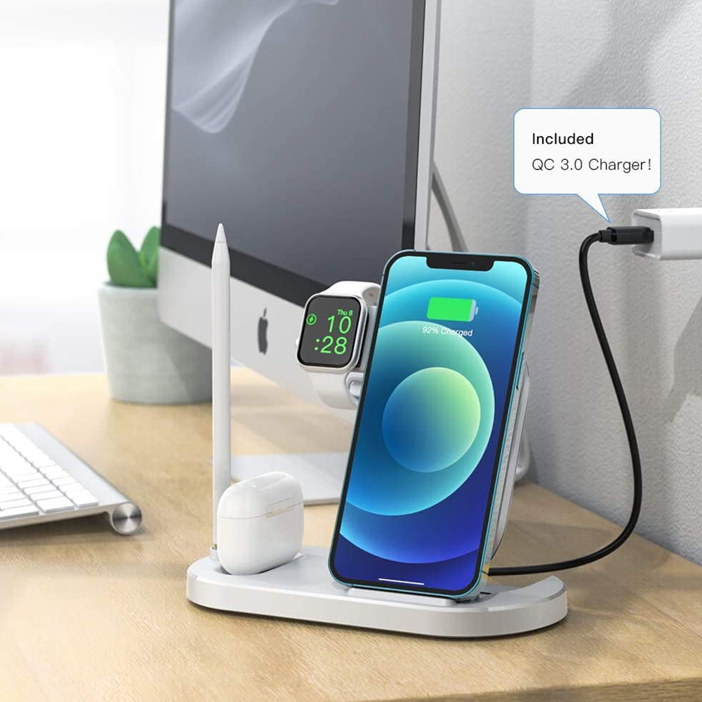 Eine Ladestation mit einem blauen Telefon, einer weißen Smartwatch, einem Stift und Ohrhörern auf einem Schreibtisch in der Nähe eines Computers.