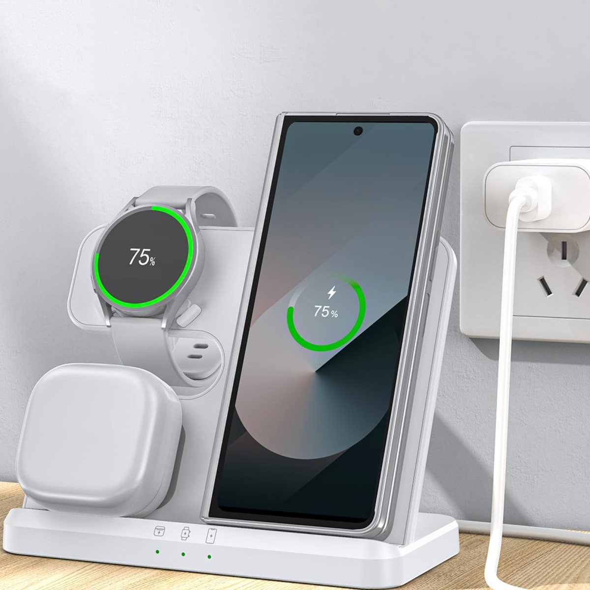Eine weiße Ladestation mit einem Telefon und einer Uhr, die jeweils 75 % Akku anzeigen, vor einer neutralen Wand.