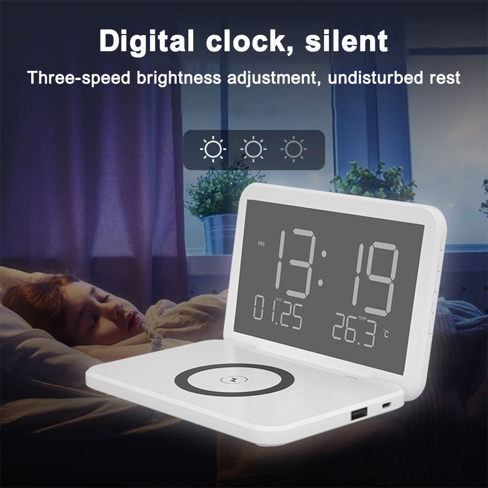 Ein weißes Ladepad mit einer Digitaluhr, die Uhrzeit, Datum und Temperatur anzeigt, mit einem Kind, das im Hintergrund schläft.