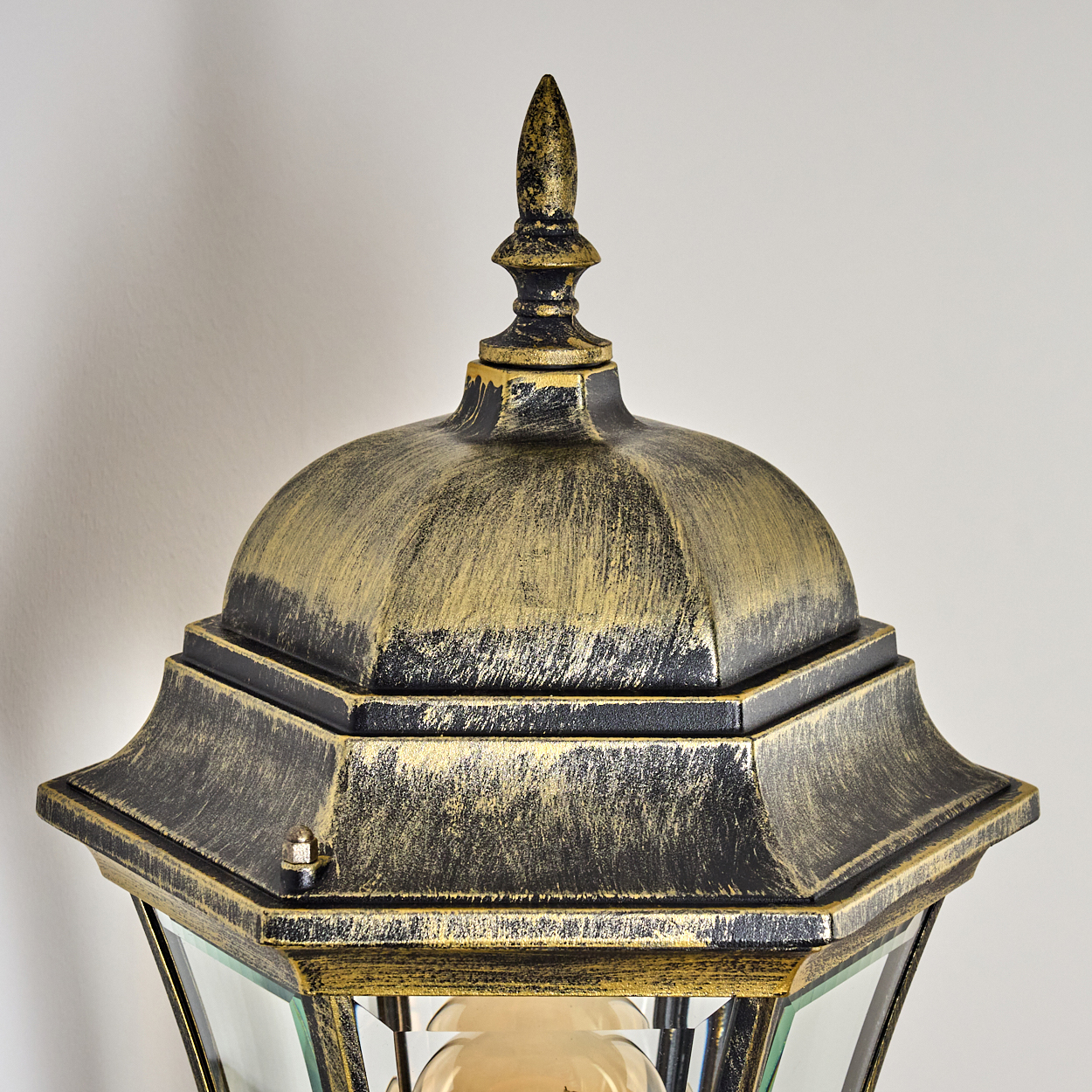Eine Nahaufnahme einer bronzefarbenen Außenwandleuchte mit klarem Glas und Glühbirne.