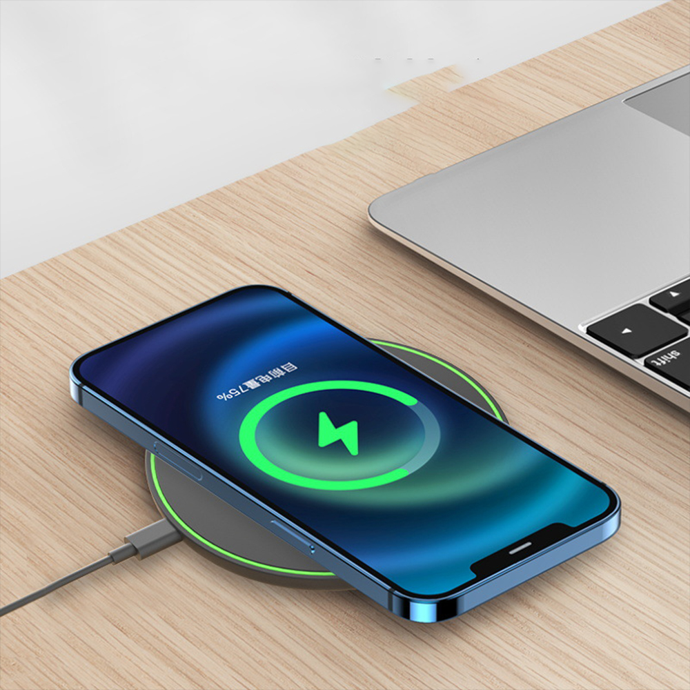 Ein blaues Telefon mit einem Ladesymbol auf dem Bildschirm wird drahtlos neben einem Laptop aufgeladen.