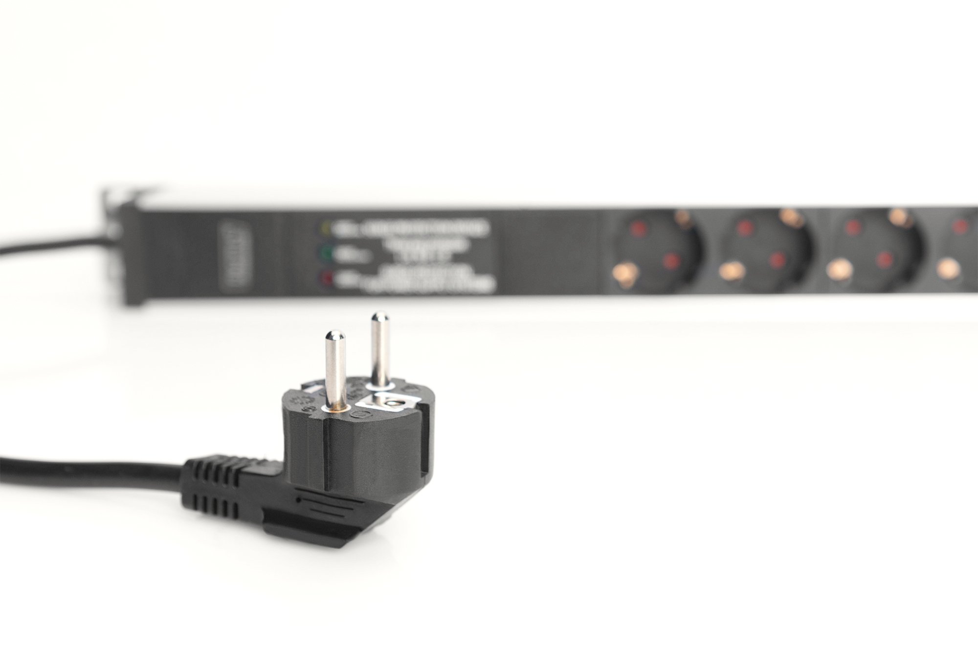 Wtyczka zasilania znajduje się na pierwszym planie, a listwa przeciwprzepięciowa w tle na białej powierzchni.