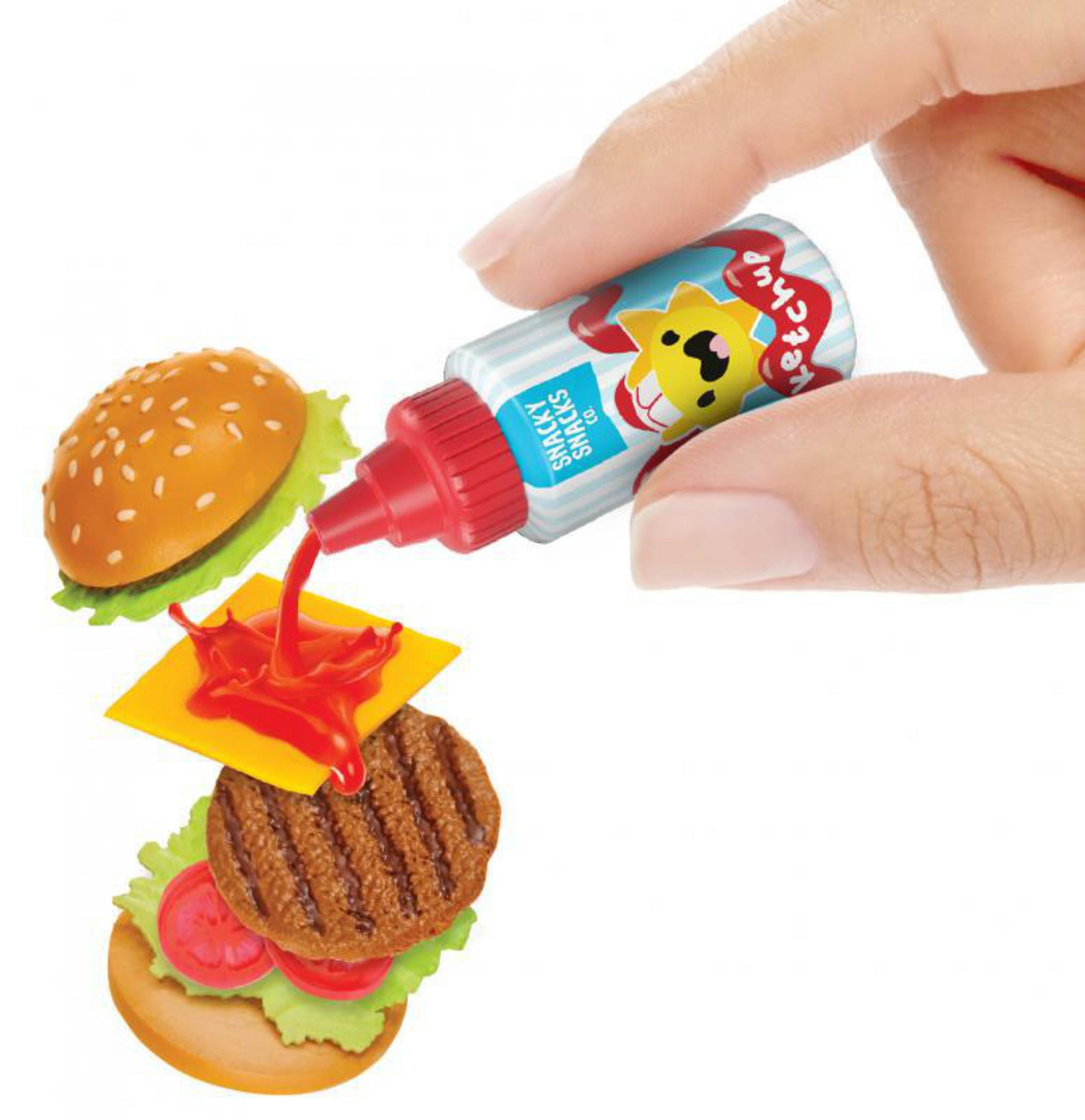 Hand gießt Ketchup auf einen Miniatur-Burger mit Käse und Belag.