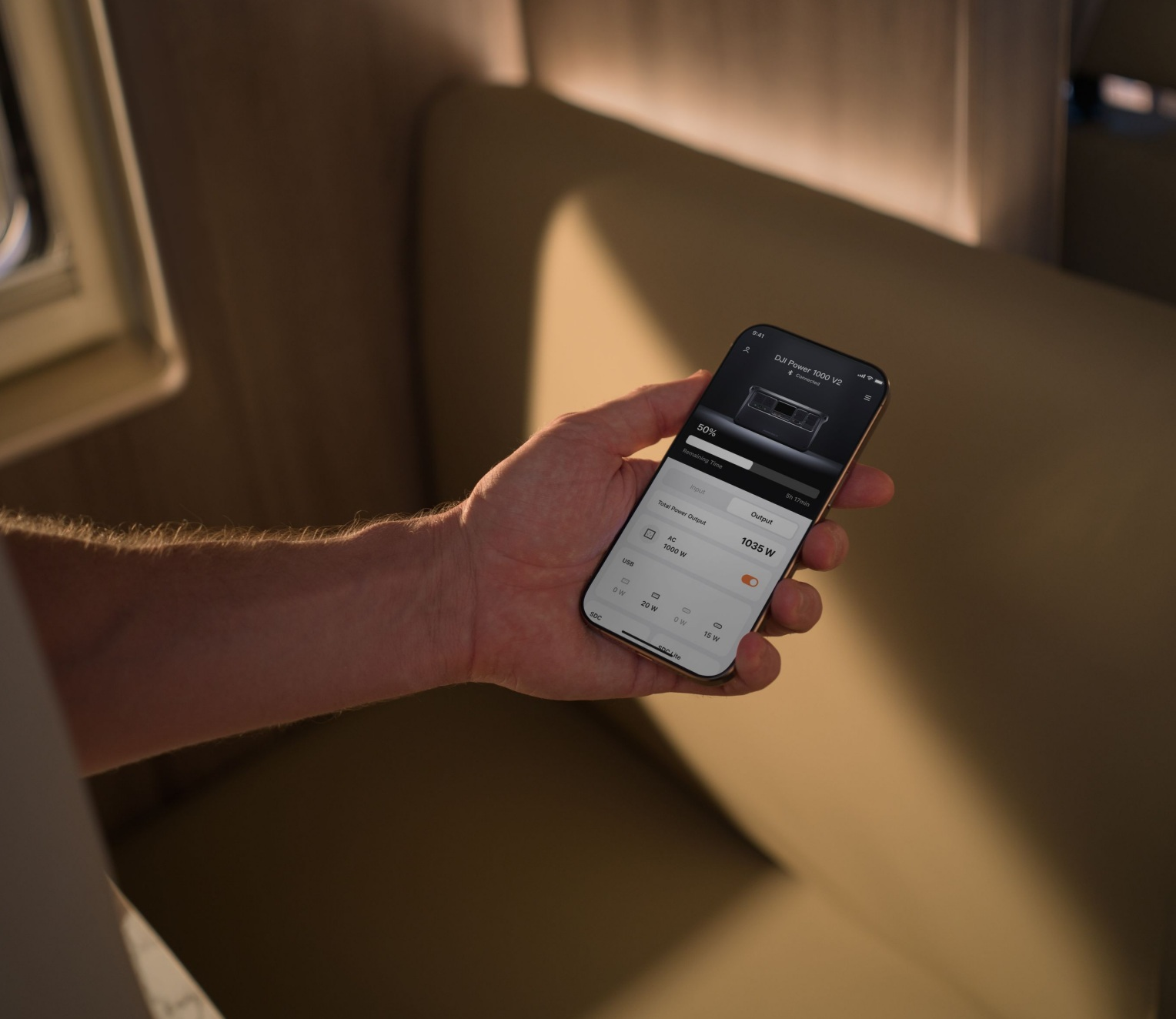 Die Hand einer Person, die ein Smartphone mit einer Powerstation-Oberfläche hält, mit verschwommenem Hintergrund.