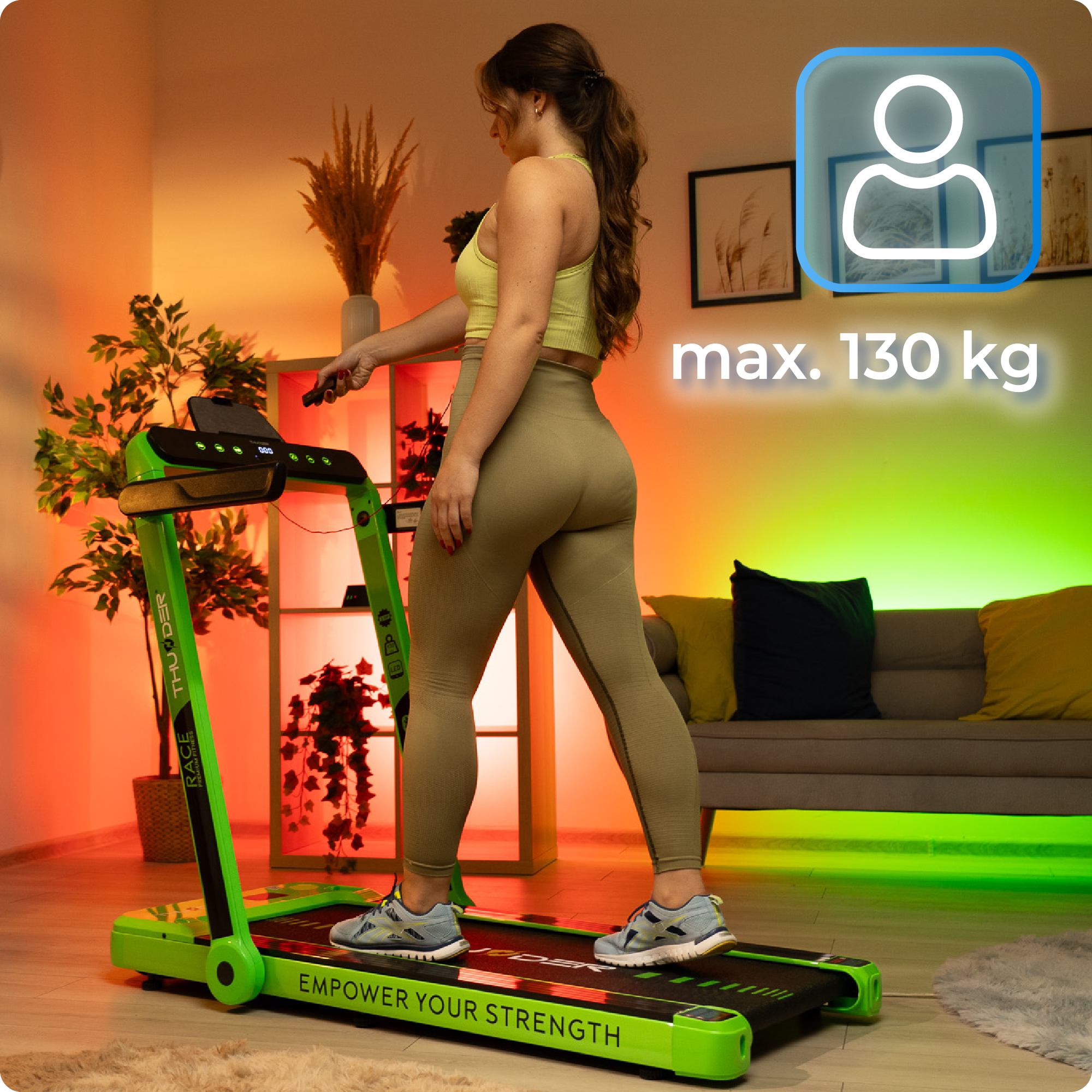 Kobieta na bieżni. Trzyma pilota, a wyświetlacz pokazuje maksymalną dozwoloną wagę.