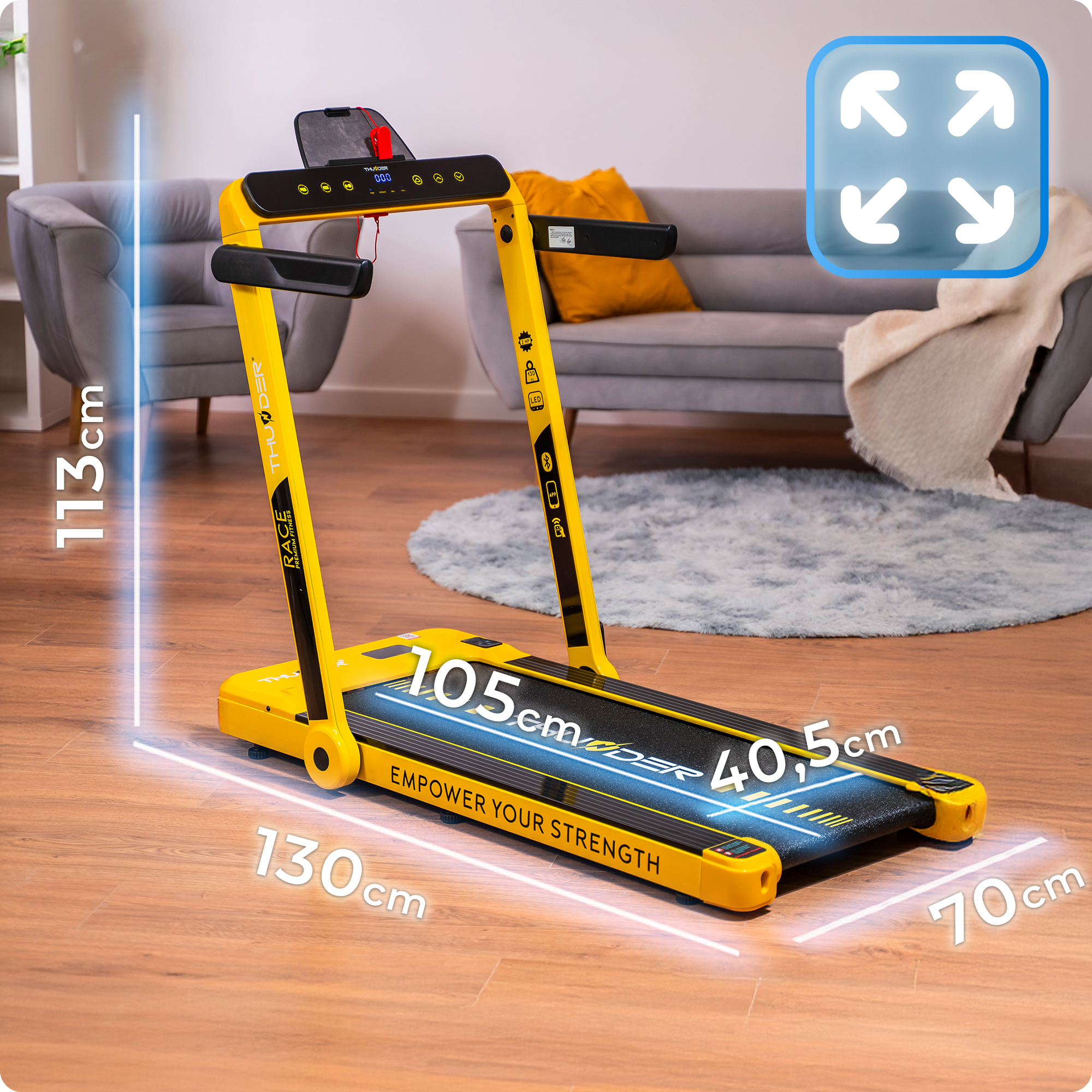 Żółta bieżnia jest wyświetlana z wymiarami w salonie, prezentując jej rozmiar i funkcje.