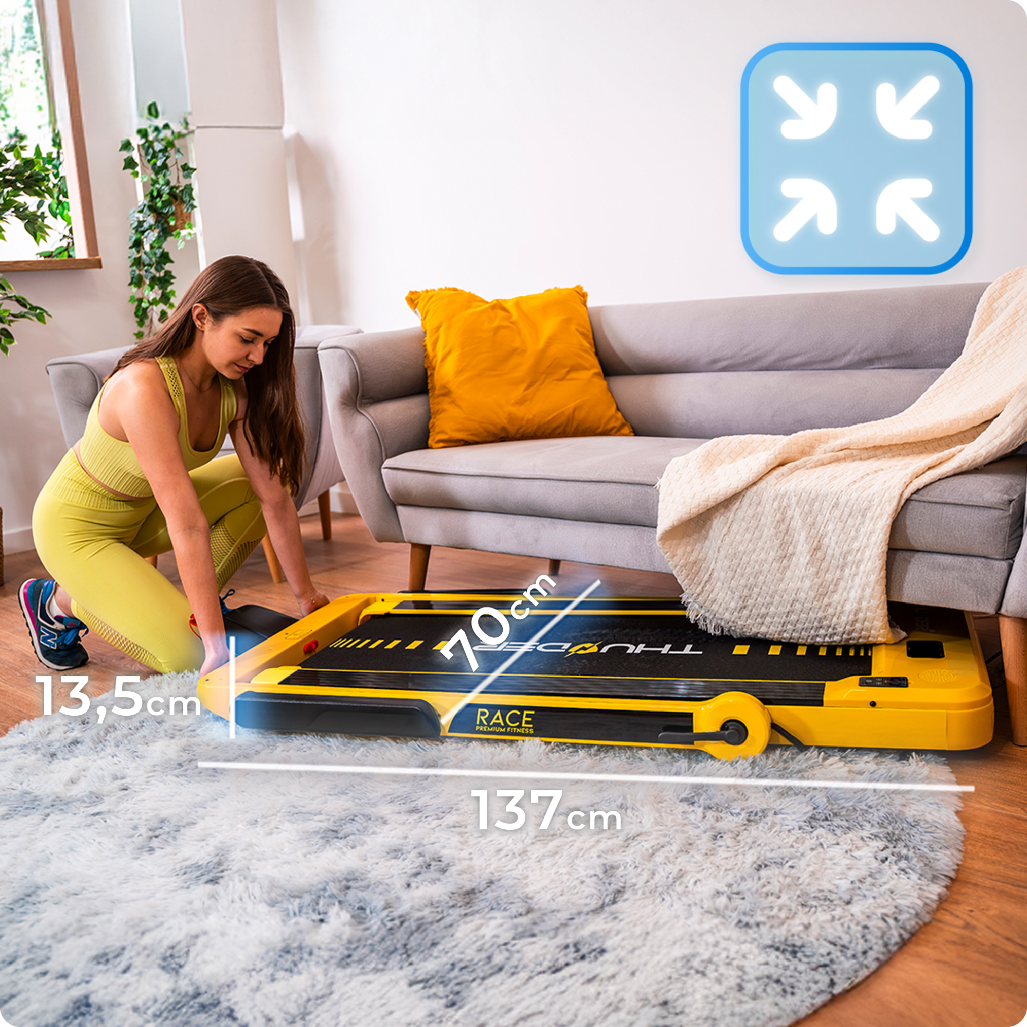 Kobieta ustawia złożoną żółtą bieżnię na dywanie, pokazując jej kompaktowy rozmiar i łatwe przechowywanie.