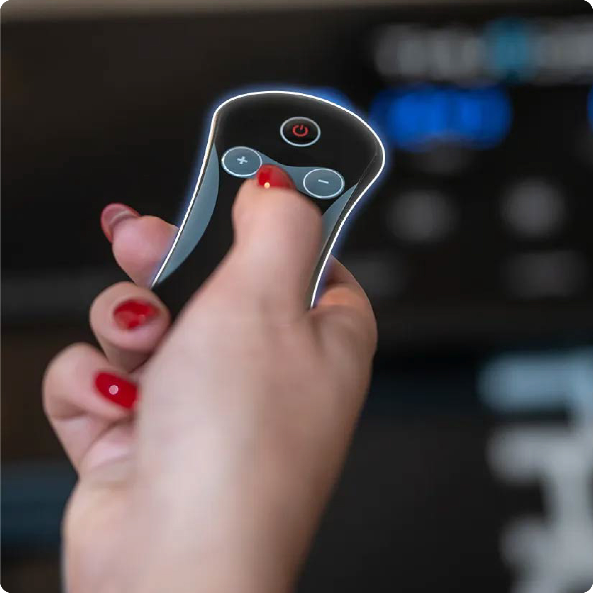 Ręka z czerwonym lakierem do paznokci trzyma czarny pilot z przyciskami plus, minus i zasilania.