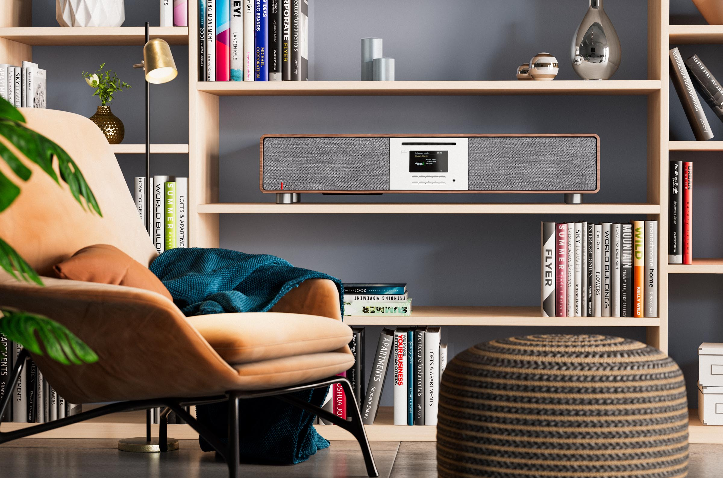 Stereo system on a bookshelf, books, armchair, and a floor pouf.