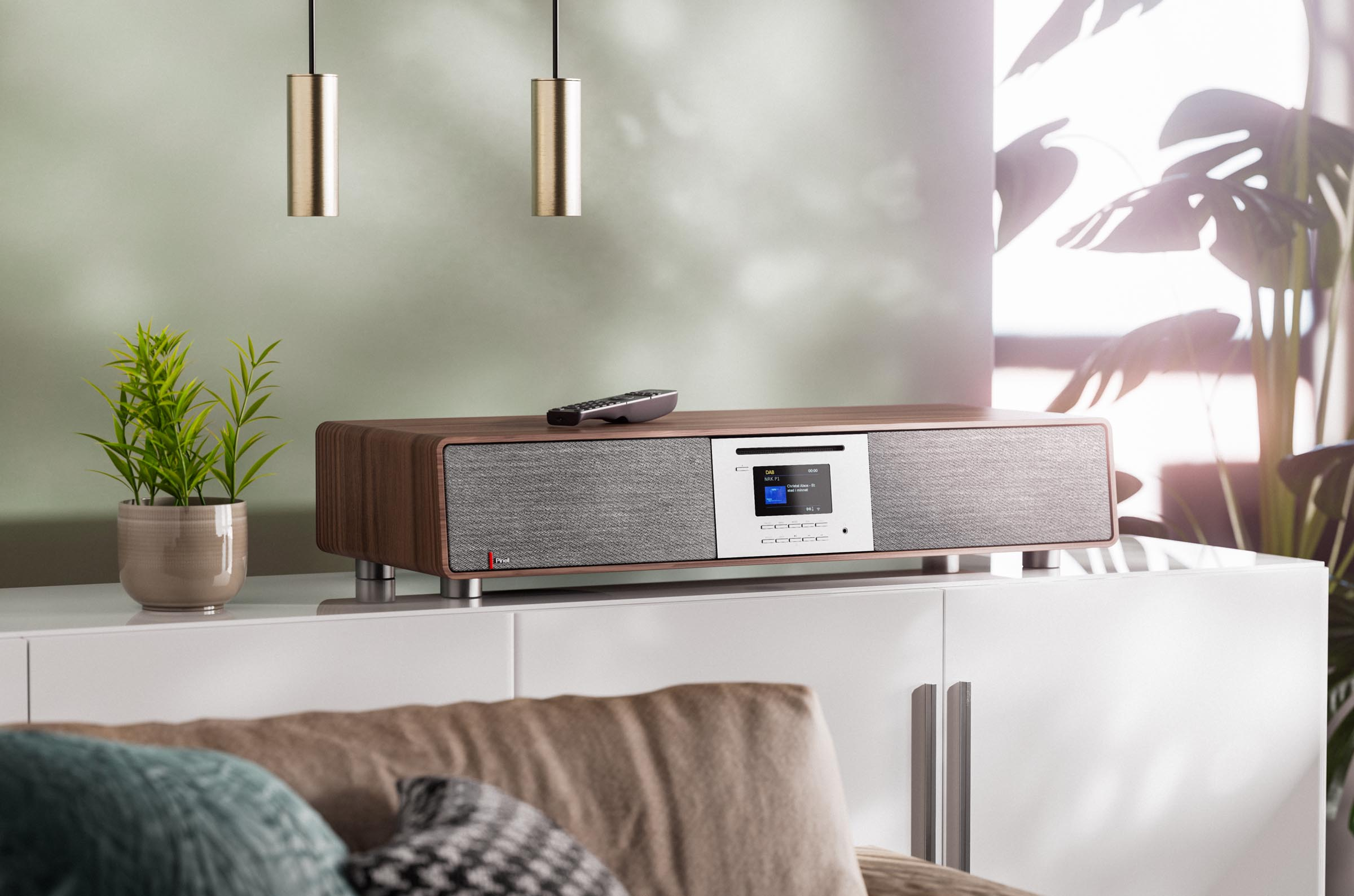 Stereo system on a white cabinet. A remote control and a potted plant.