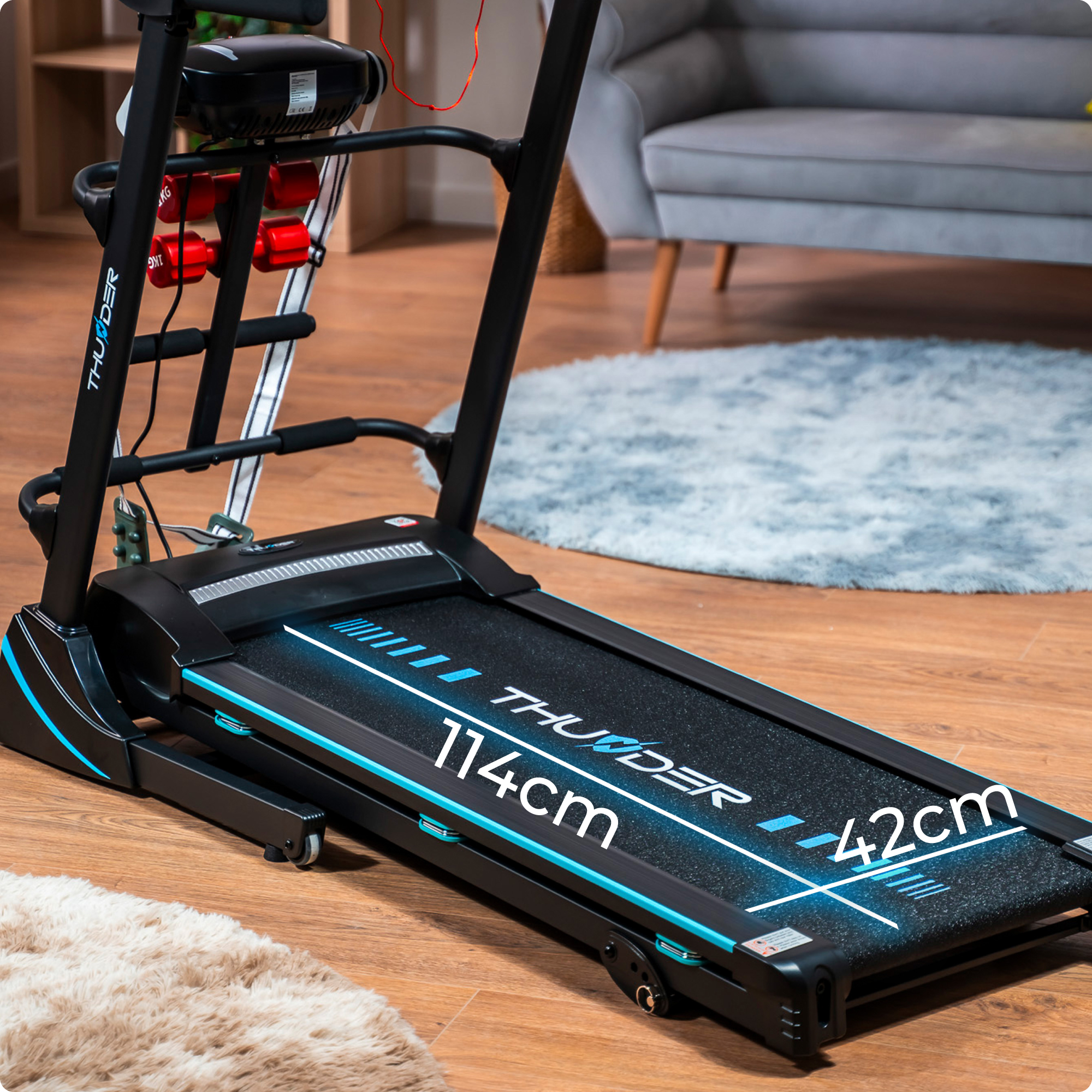 Czarna bieżnia z niebieskimi akcentami na drewnianej podłodze. Wymiary oznaczone białym tekstem.