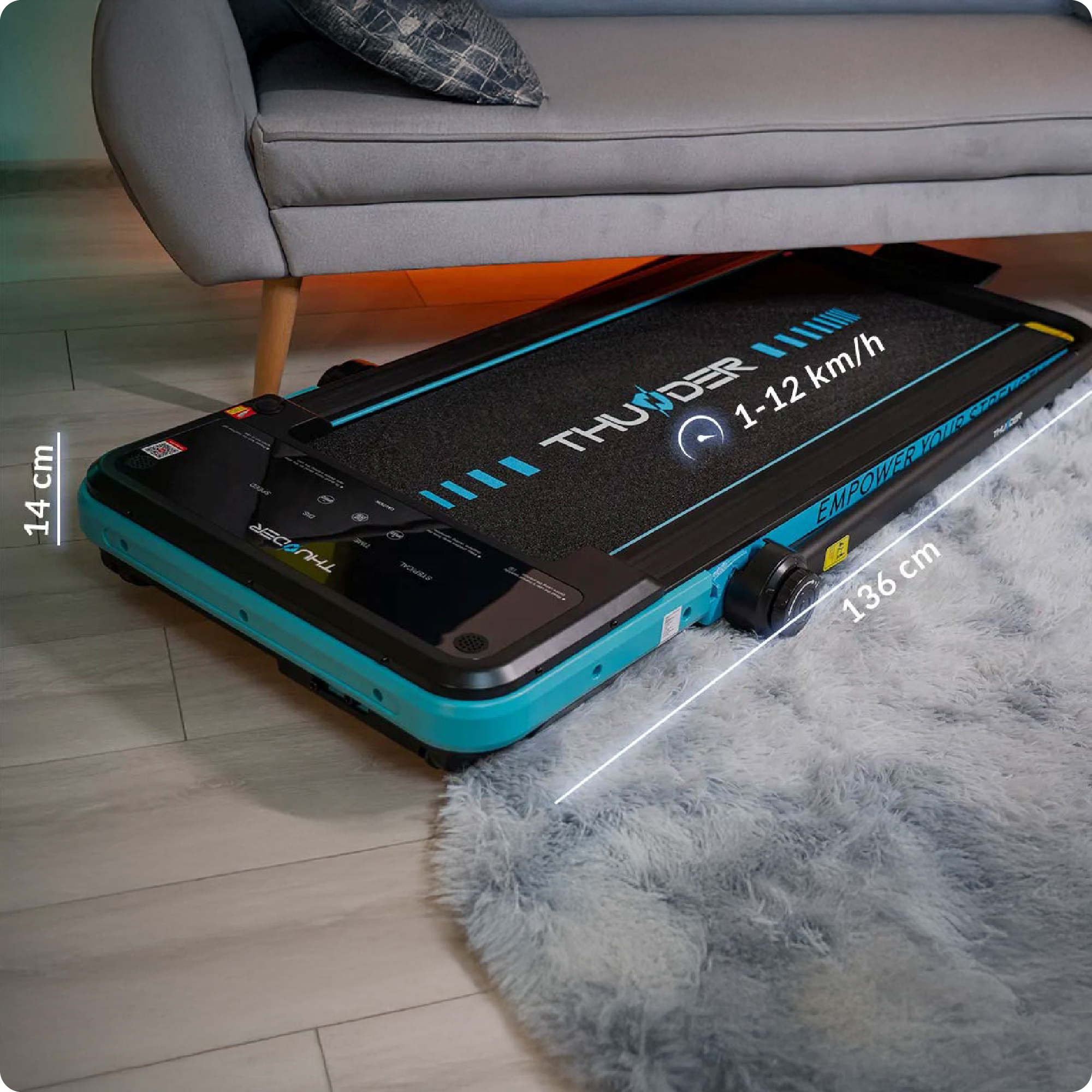 Złożona czarno-niebieska bieżnia jest przechowywana pod szarą sofą.