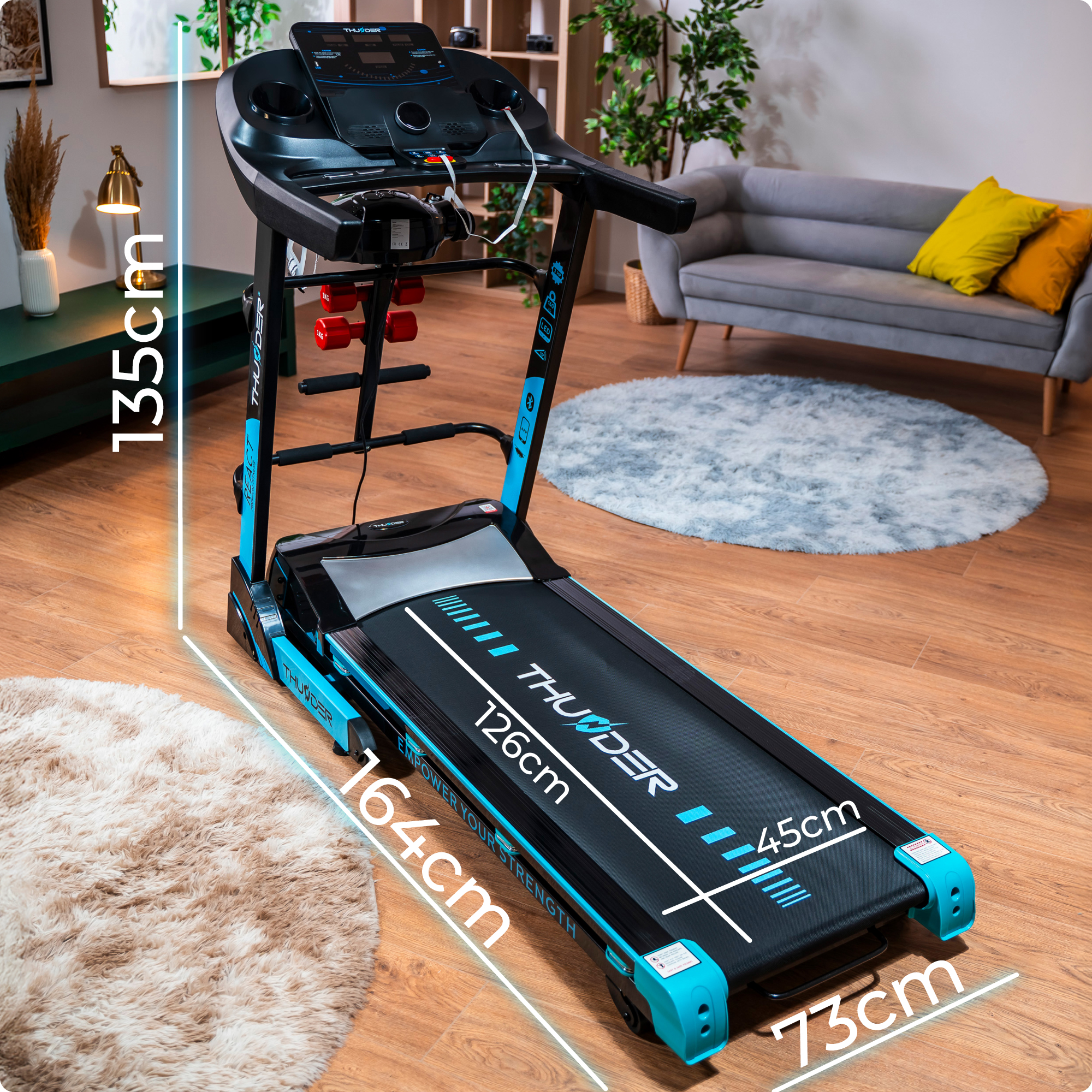 Bieżnia z wymiarami nałożonymi na obraz, umieszczona w salonie.