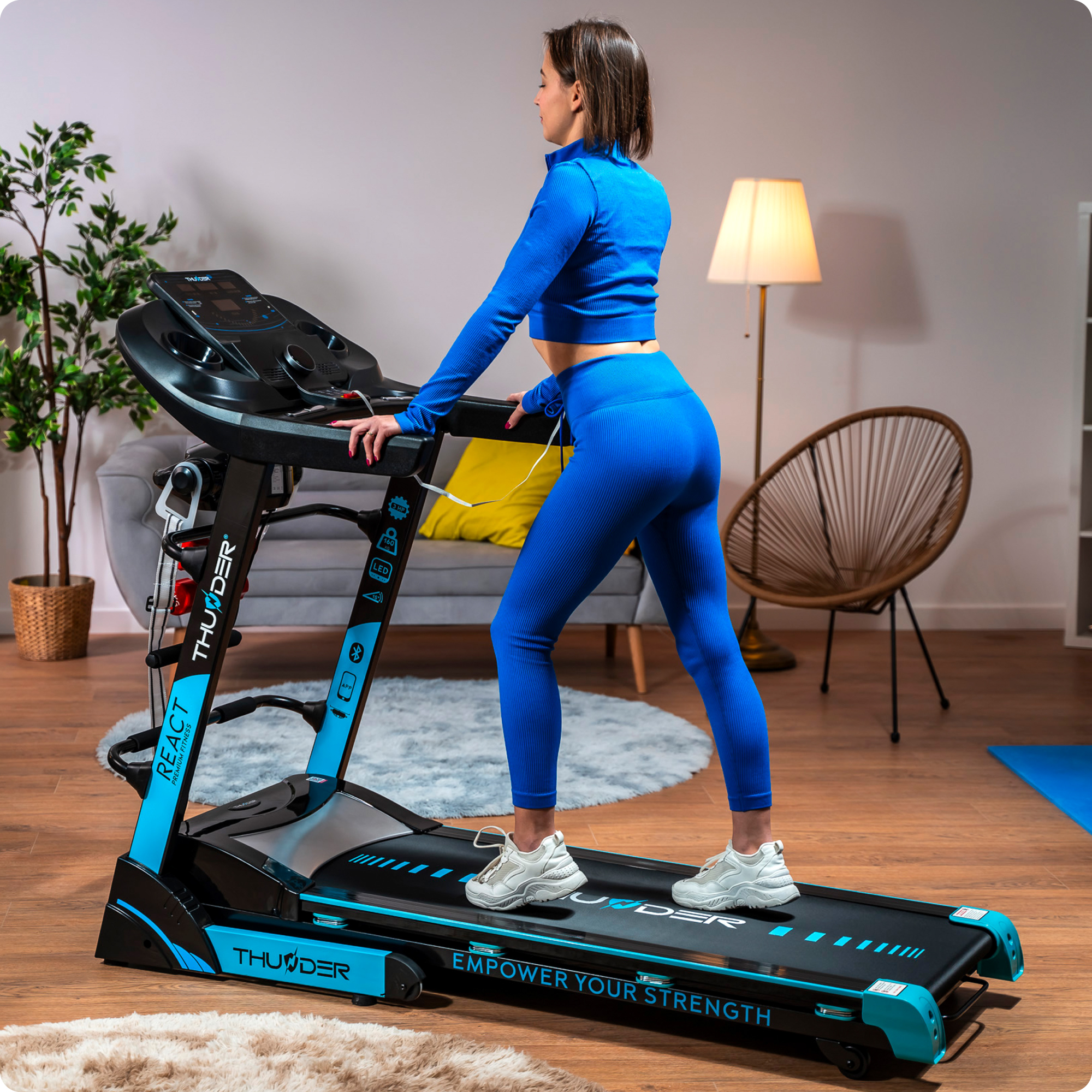 Kobieta w niebieskim stroju do ćwiczeń na czarno-niebieskiej bieżni.